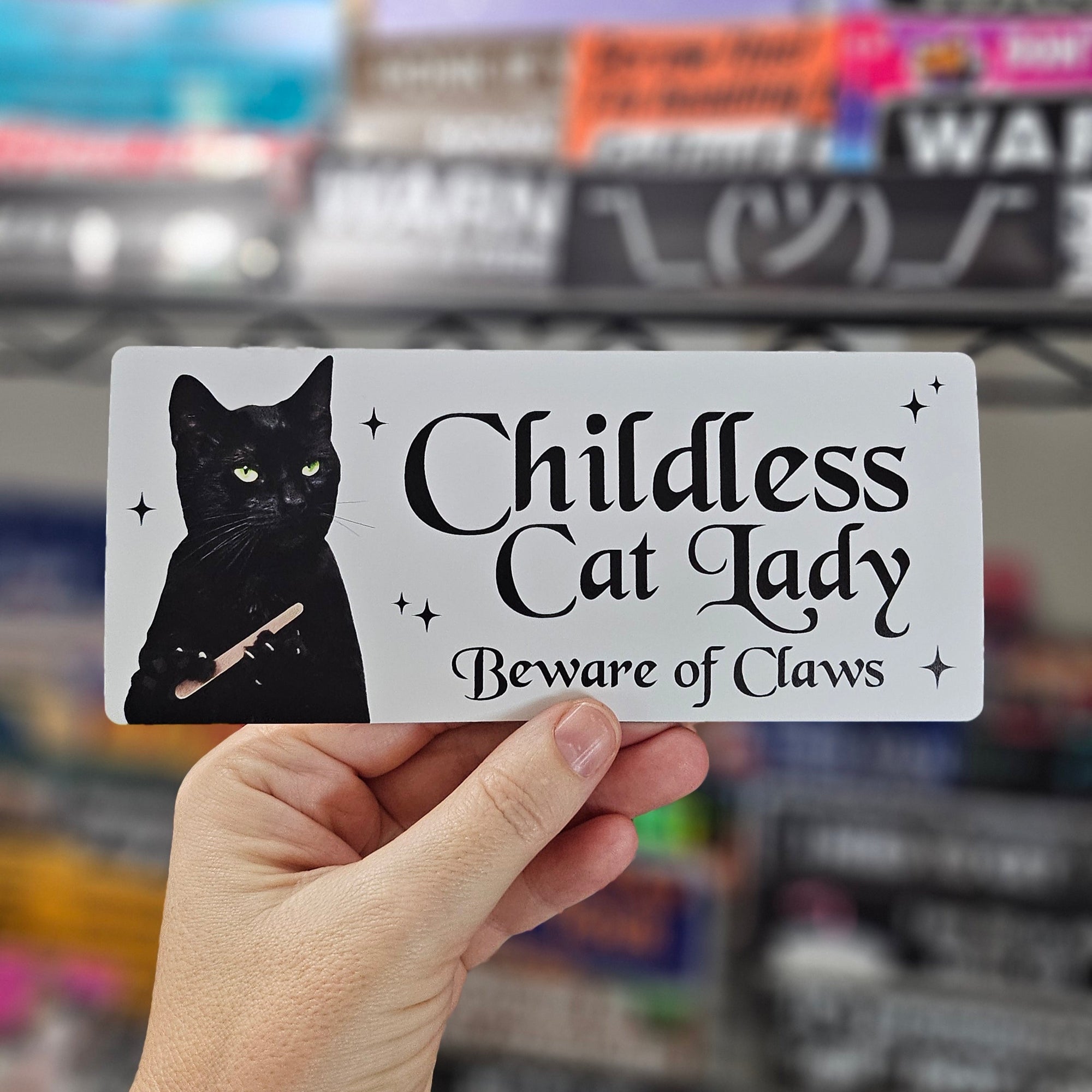 Rectangular sticker with a black cat holding a nail file beside the words “Childless Cat Lady” and “Beware of Claws,” shown in white and holographic versions.