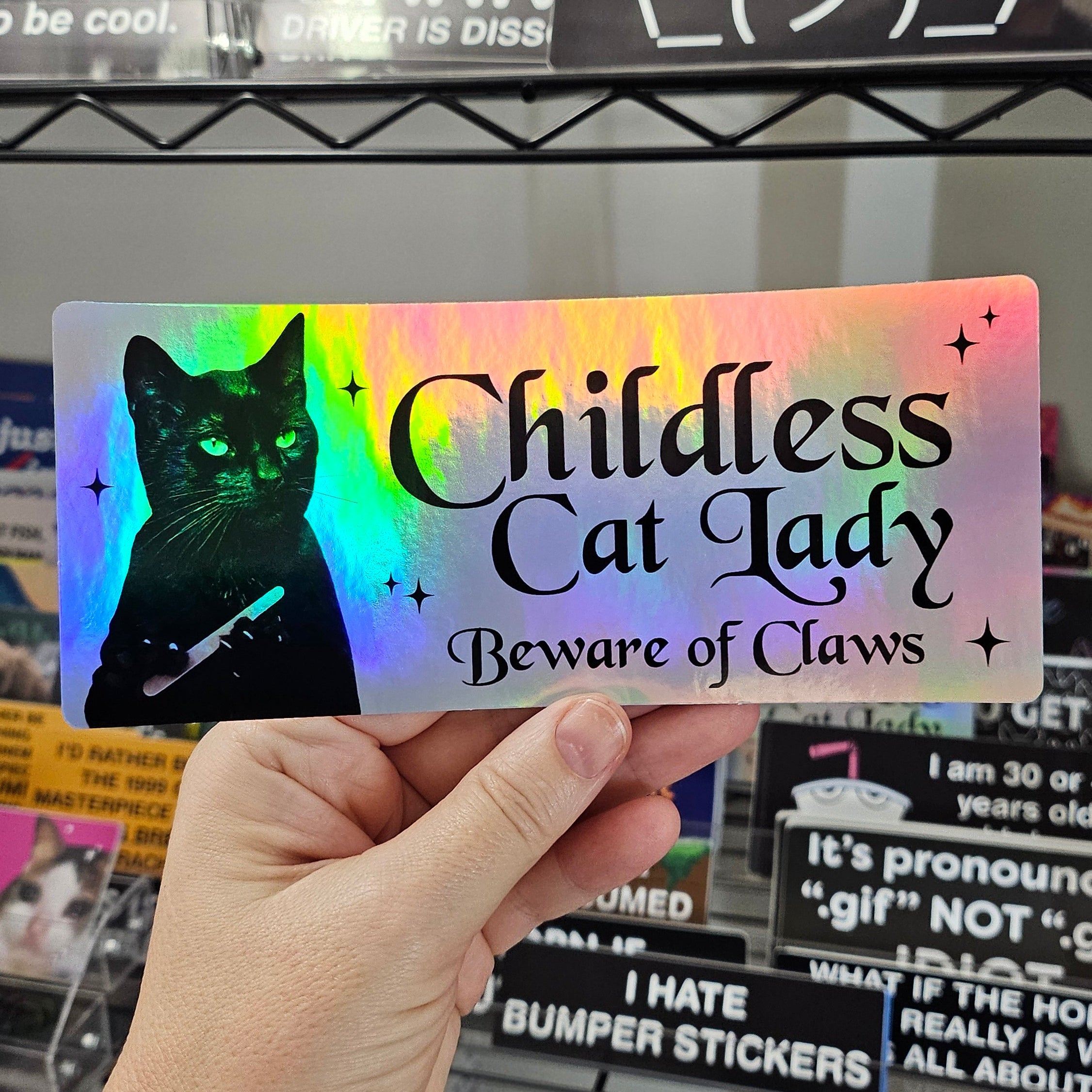 Rectangular sticker with a black cat holding a nail file beside the words “Childless Cat Lady” and “Beware of Claws,” shown in white and holographic versions.