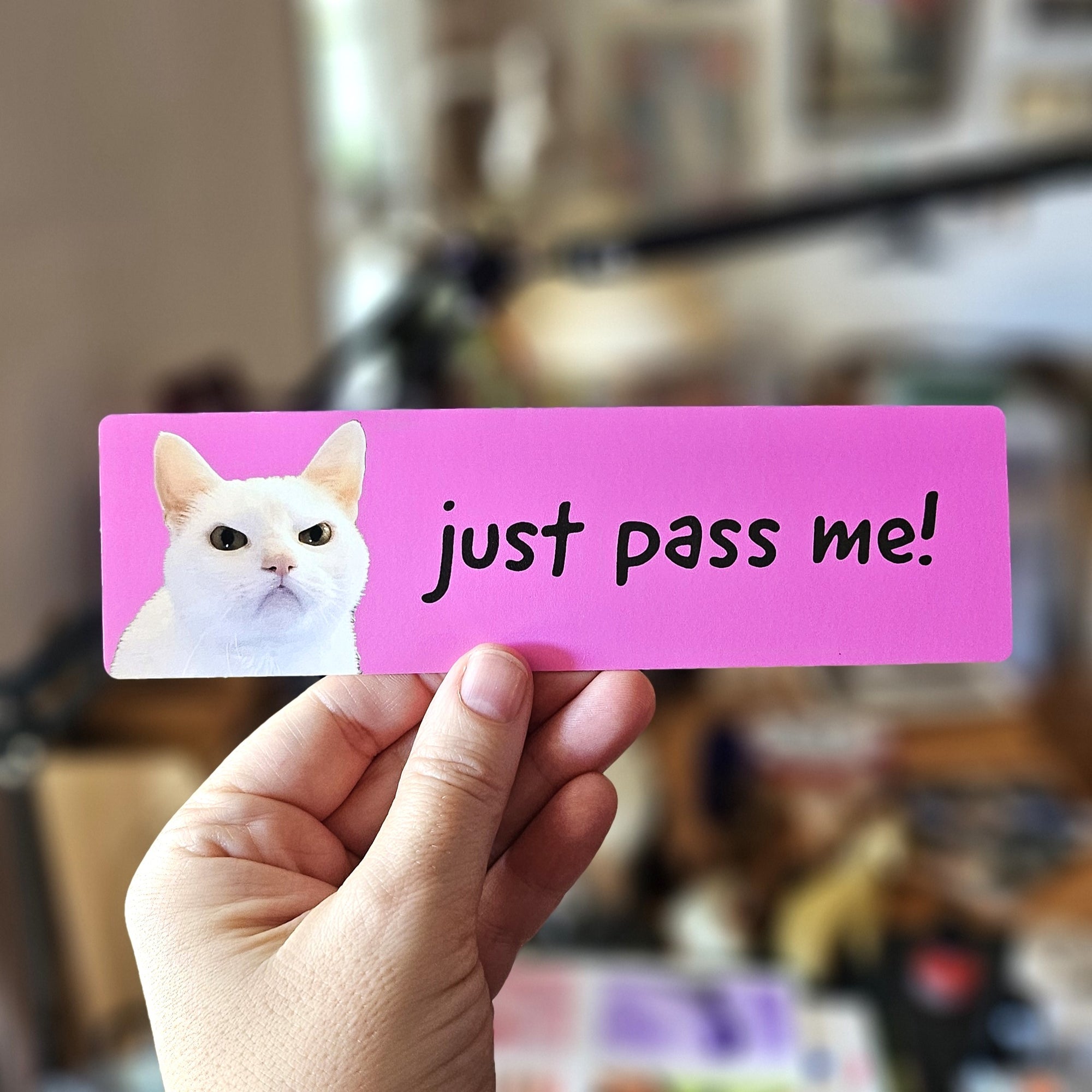 rectangular “Just Pass Me!” bumper sticker shown in pink with dramatic cat photos and bold handwritten-style text.
