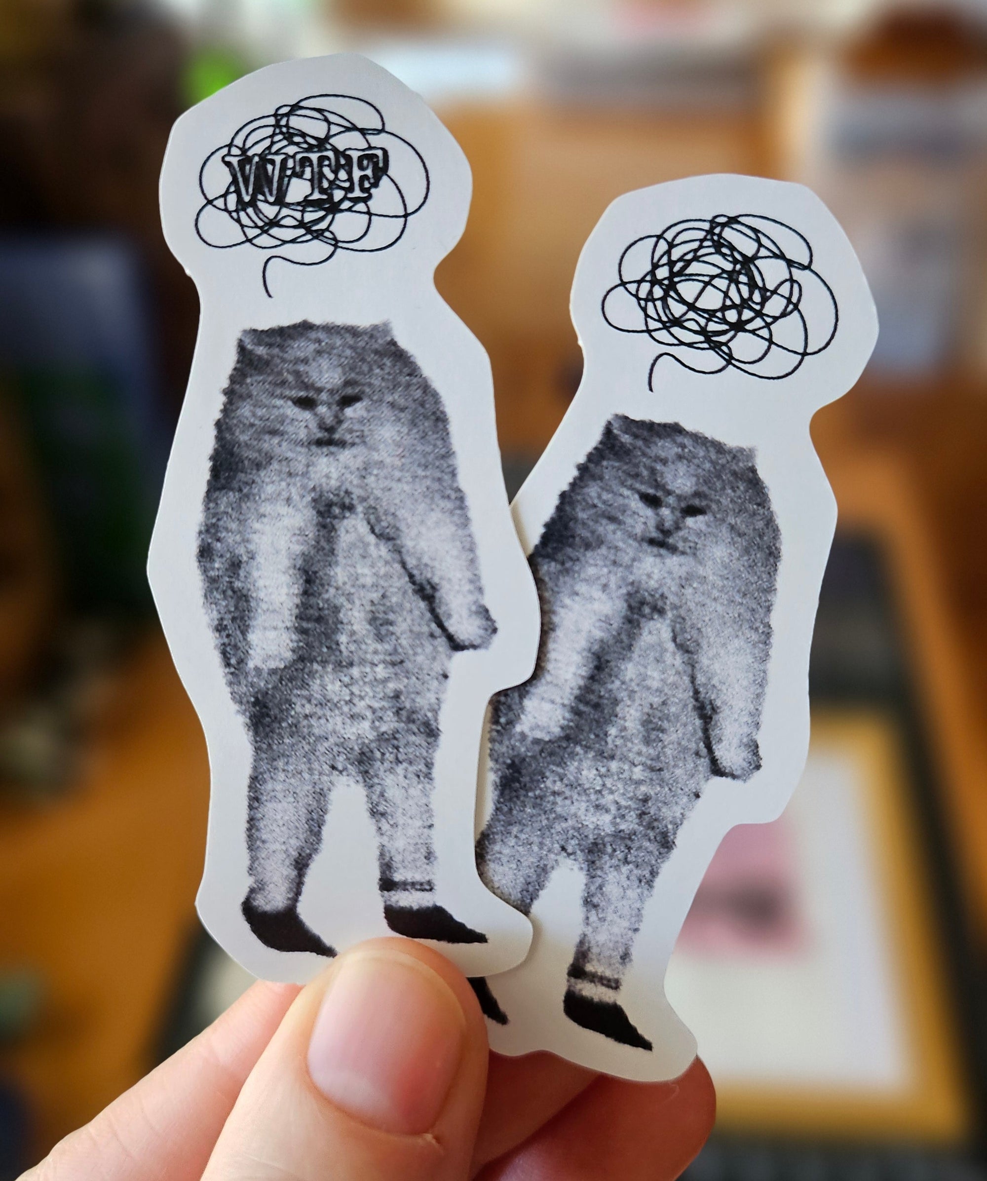 Two die cut sticker options featuring a fuzzy standing gray cat with tiny legs and a scribbly thought cloud, one with “WTF” text and one without.
