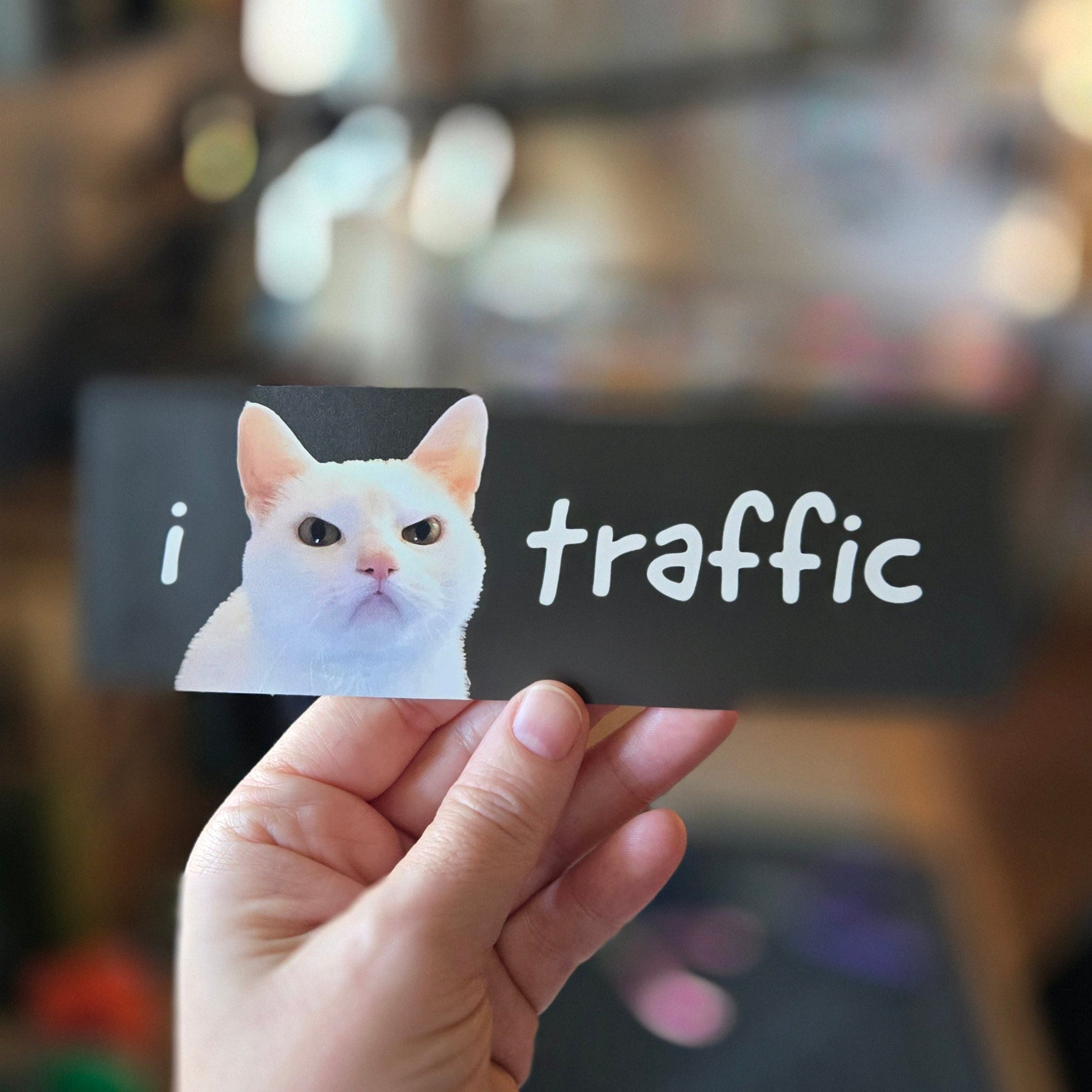 black rectangular sticker featuring a cat with 'i 😾 traffic' text on a white background