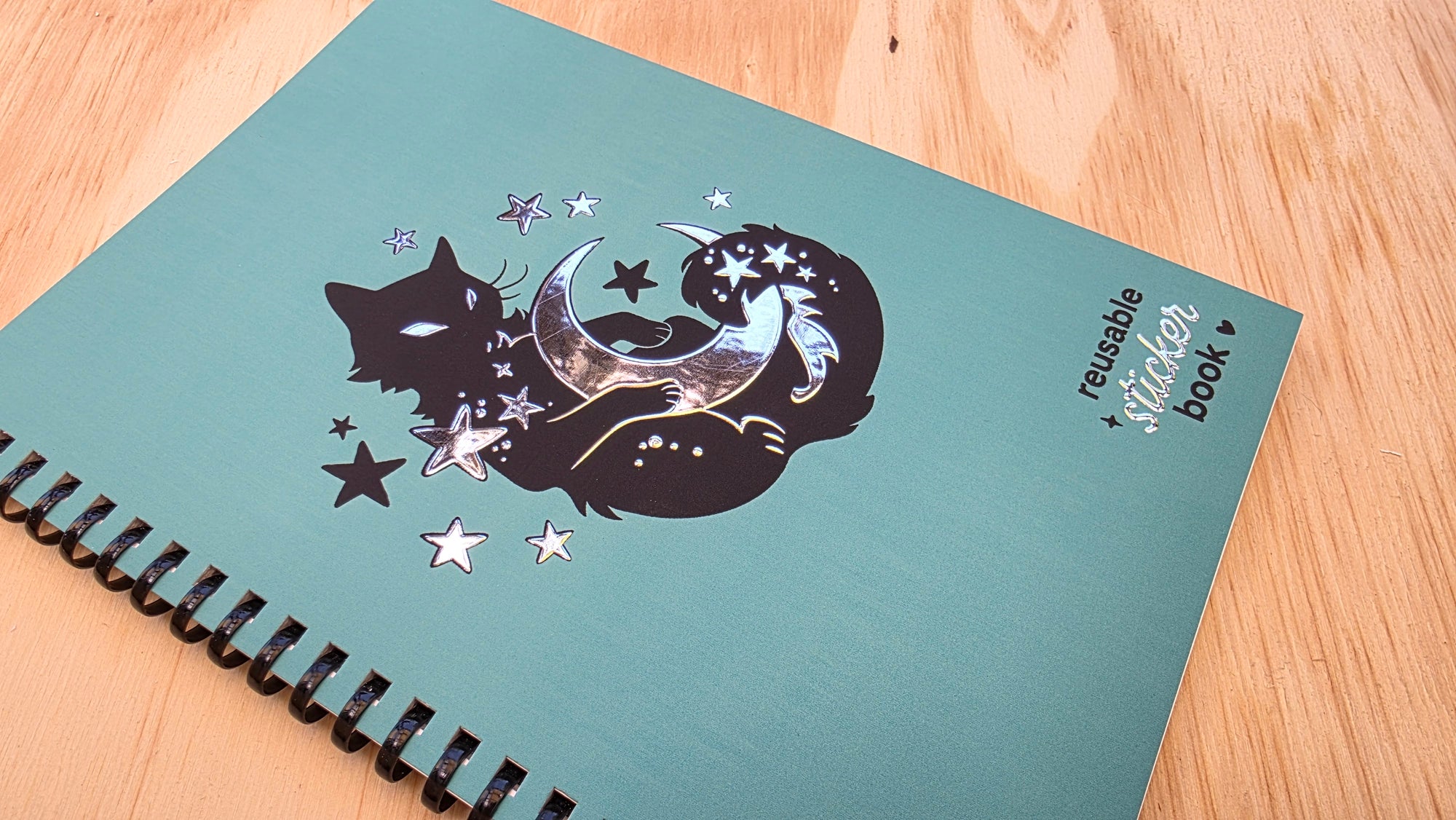 Notebook with cat and moon design on a wooden surface