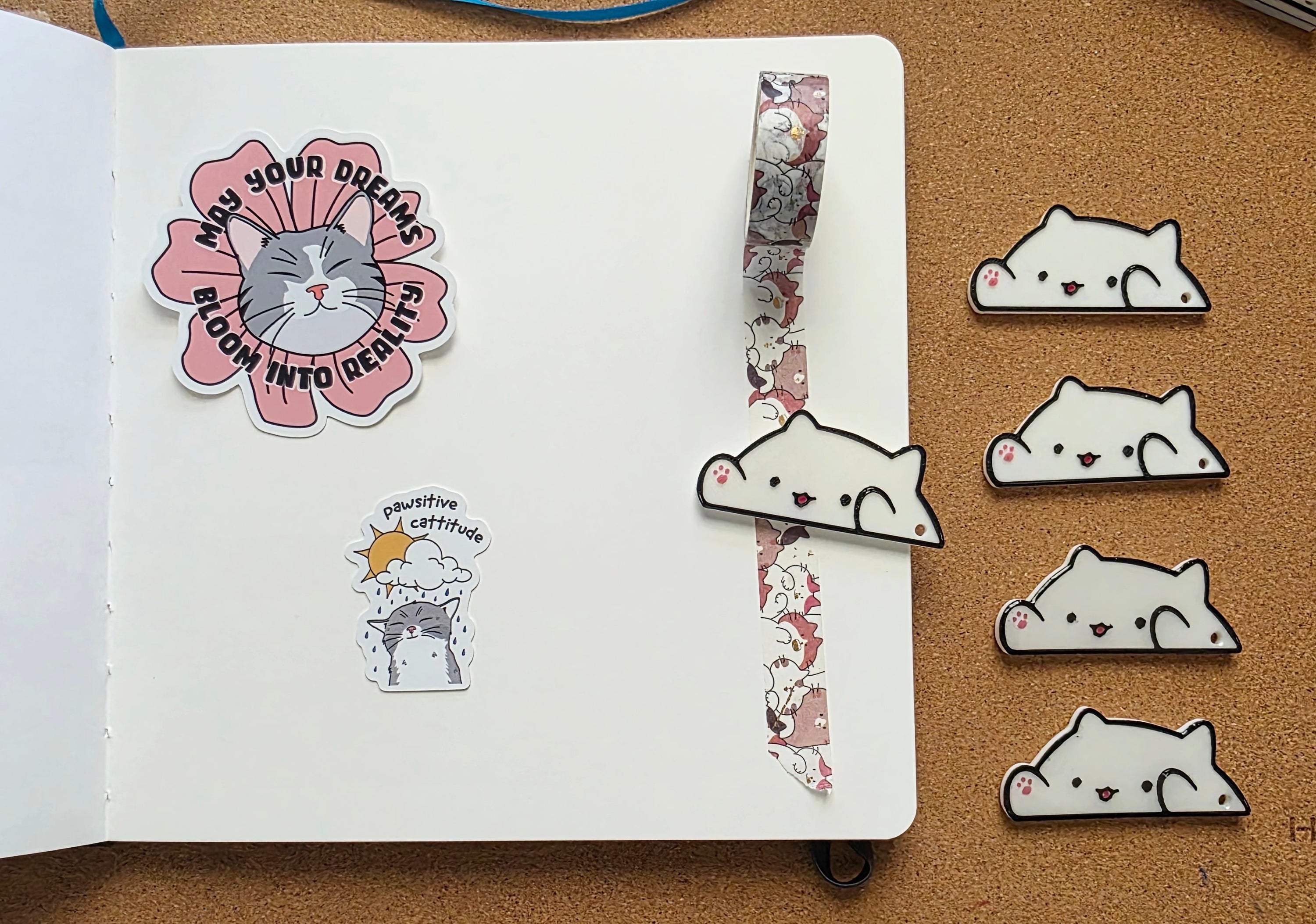 White cat-shaped 3D printed washi tape cutter with black outline, small pink paw detail, smiling face, and a hole on one end.