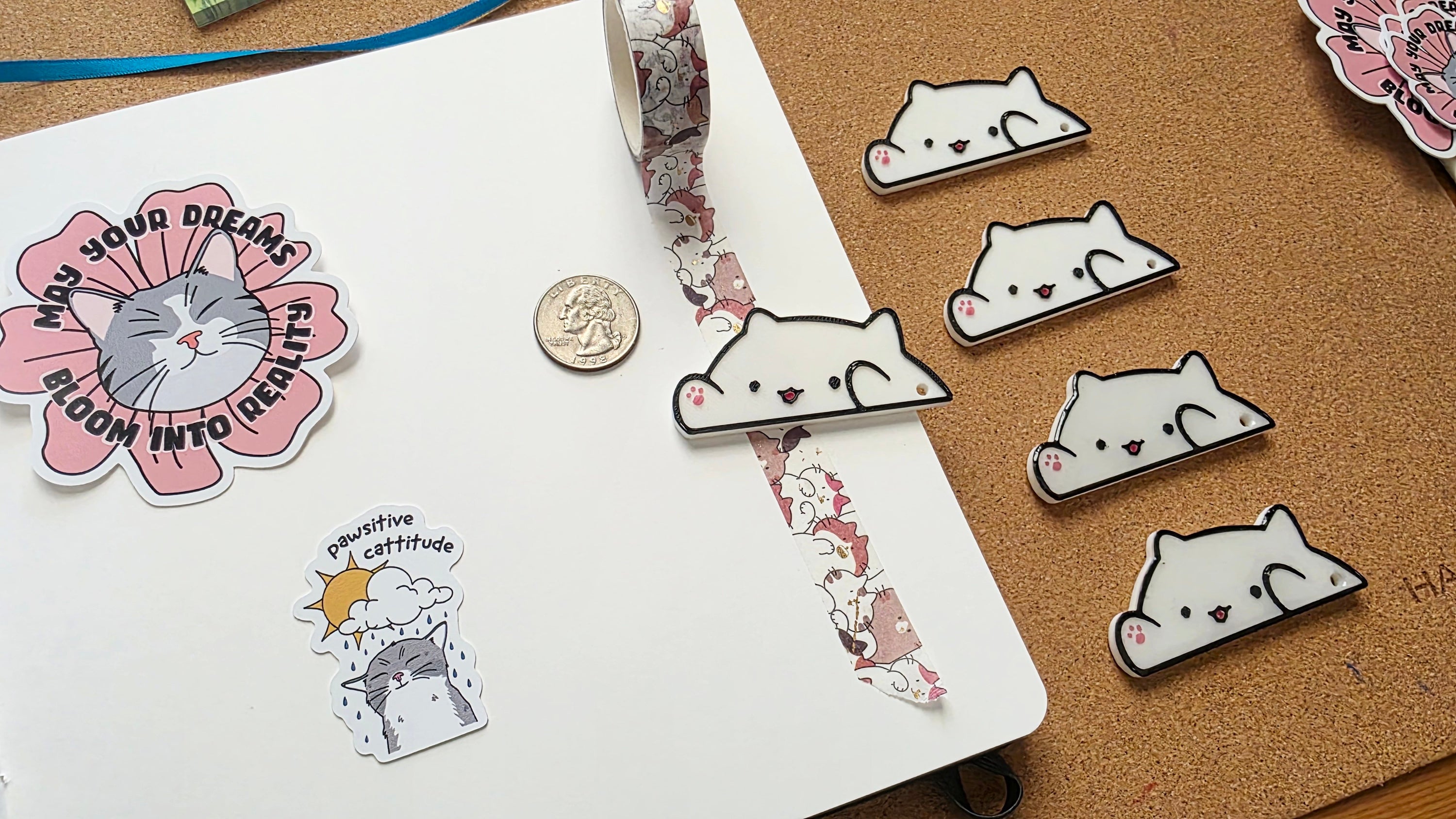 White cat-shaped 3D printed washi tape cutter with black outline, small pink paw detail, smiling face, and a hole on one end.