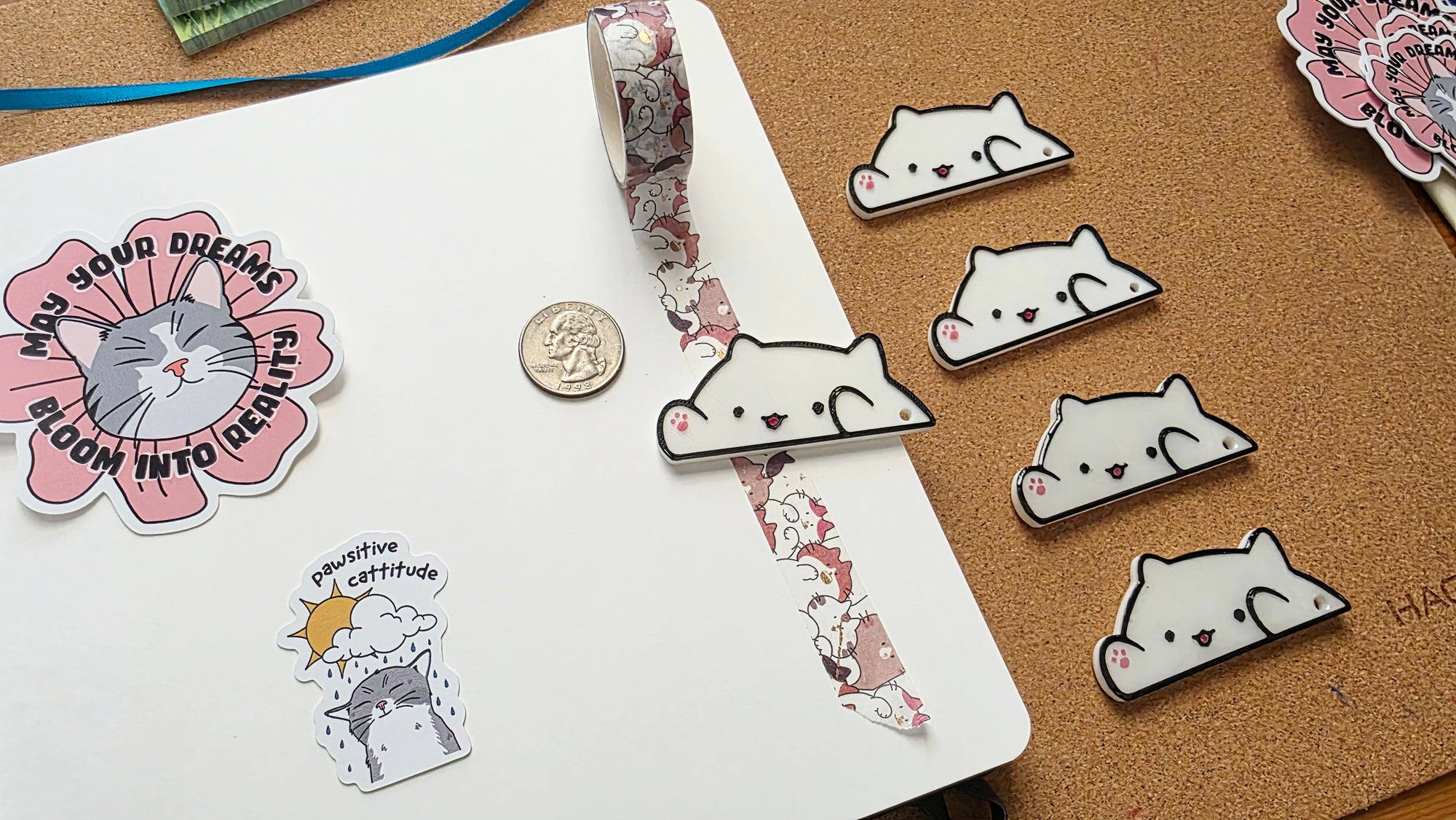 White cat-shaped 3D printed washi tape cutter with black outline, small pink paw detail, smiling face, and a hole on one end.