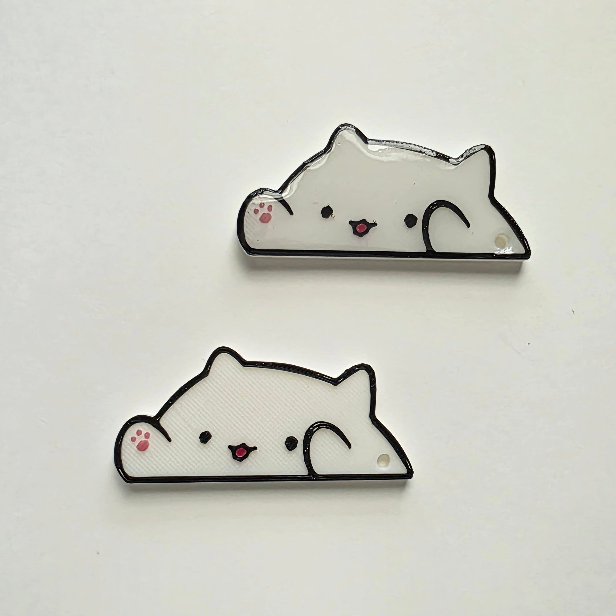 White cat-shaped 3D printed washi tape cutter with black outline, small pink paw detail, smiling face, and a hole on one end.