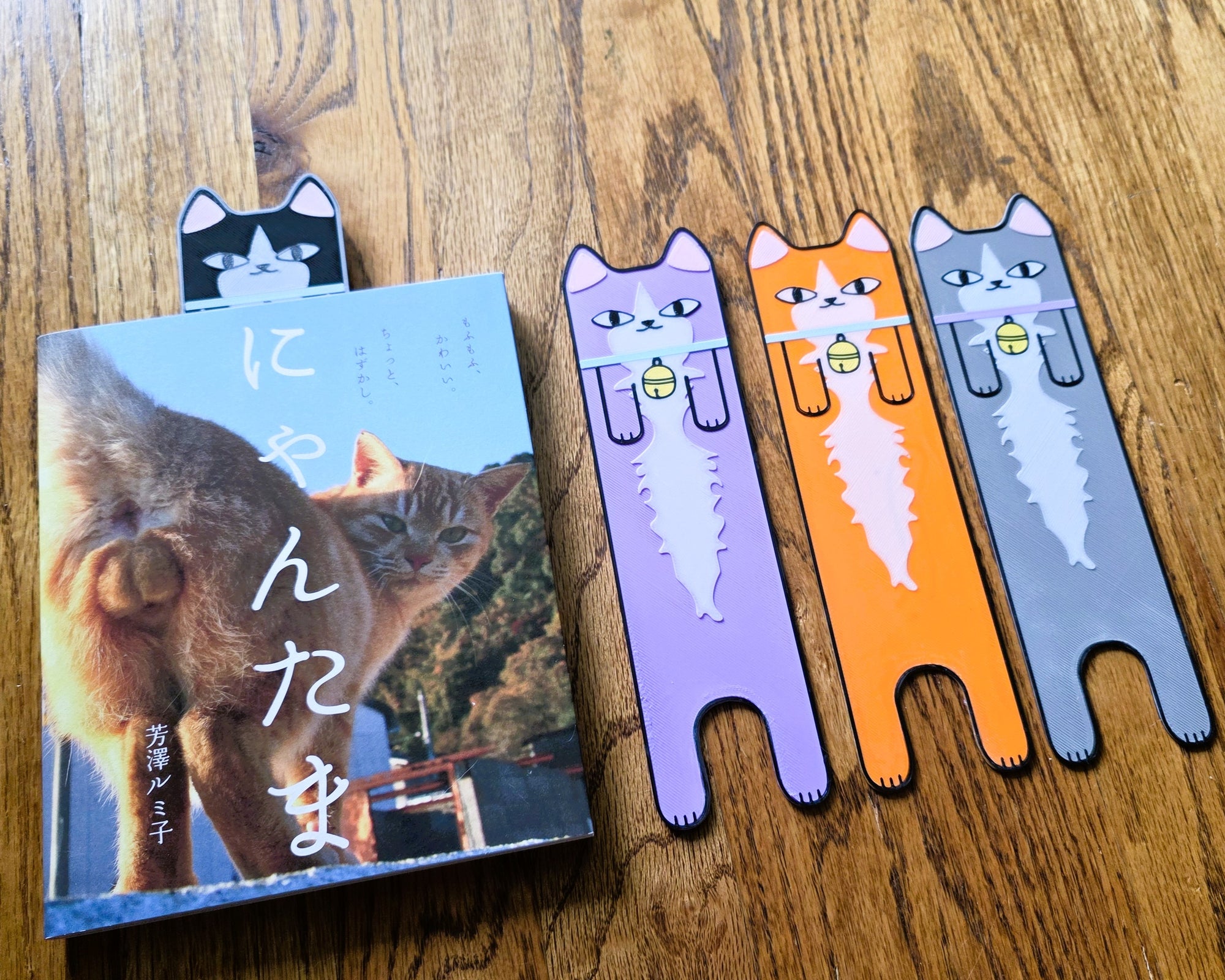 Cat-themed bookmarks and a book on a wooden surface