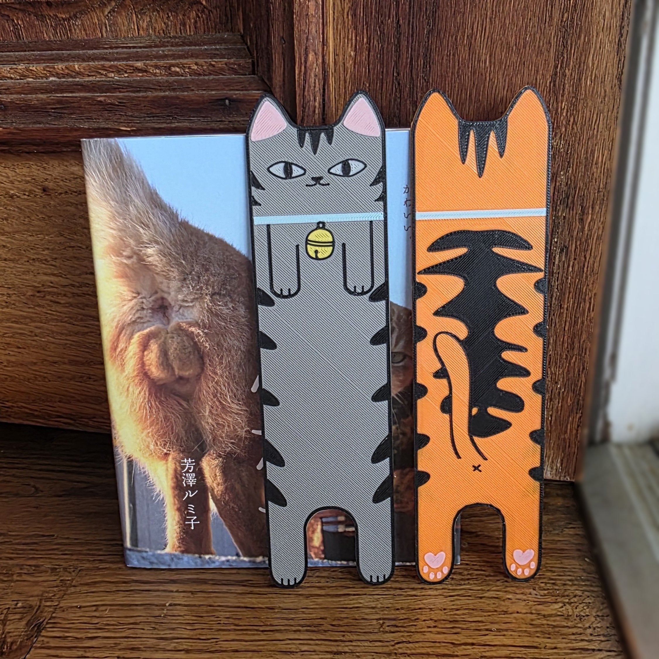 Two cat-shaped bookmarks with a wooden background