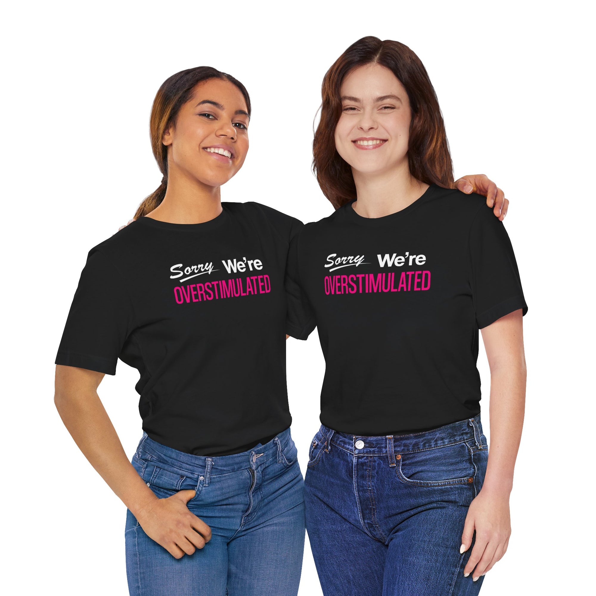 Two people wearing black t-shirt featuring the phrase “Sorry We’re Overstimulated” in white and hot pink text.
