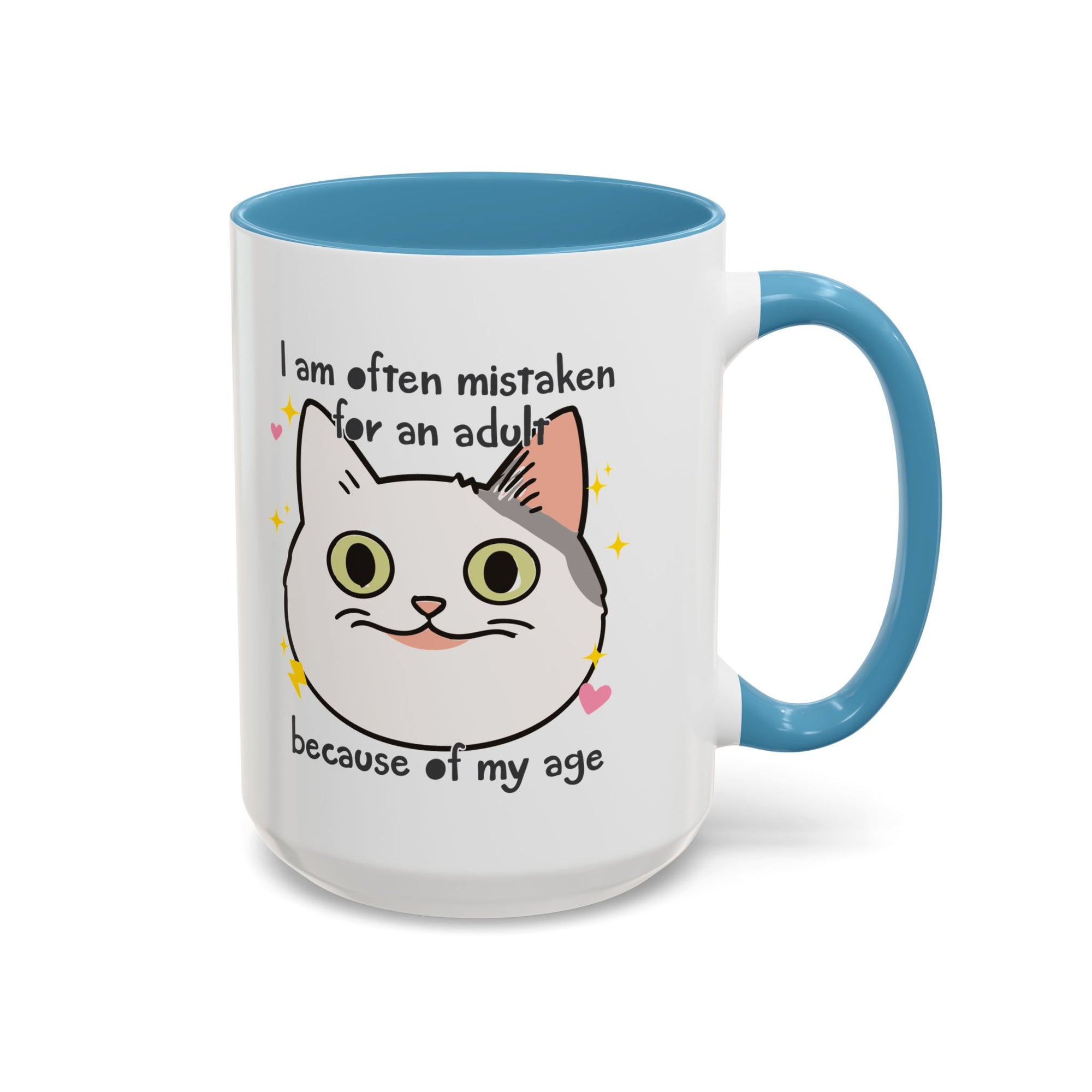 White ceramic mug with blue handle and interior featuring a cute wide-eyed cat face, hearts, sparkles, and the phrase “I am often mistaken for an adult because of my age.”
