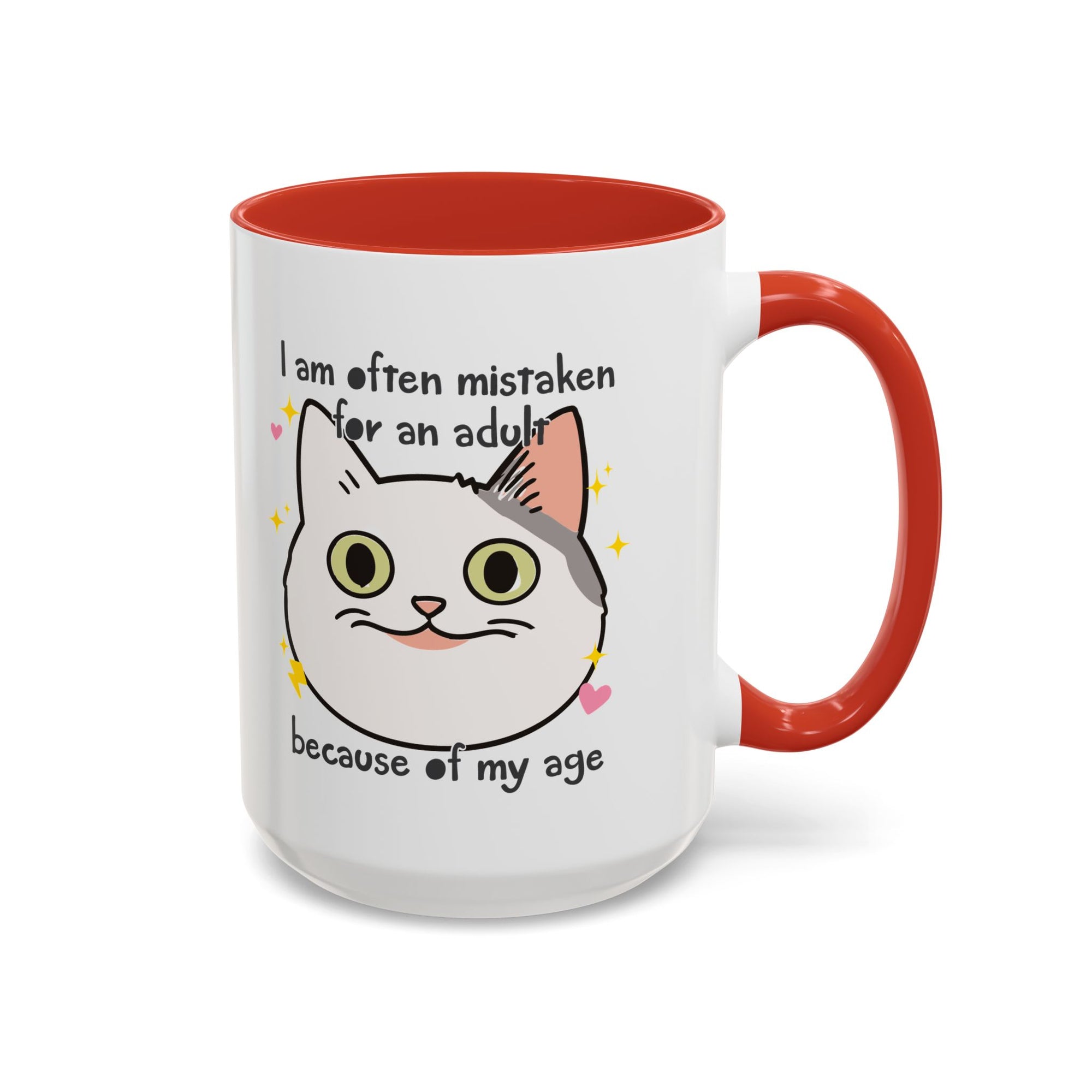 White ceramic mug with red handle and interior featuring a cute wide-eyed cat face, hearts, sparkles, and the phrase “I am often mistaken for an adult because of my age.”
