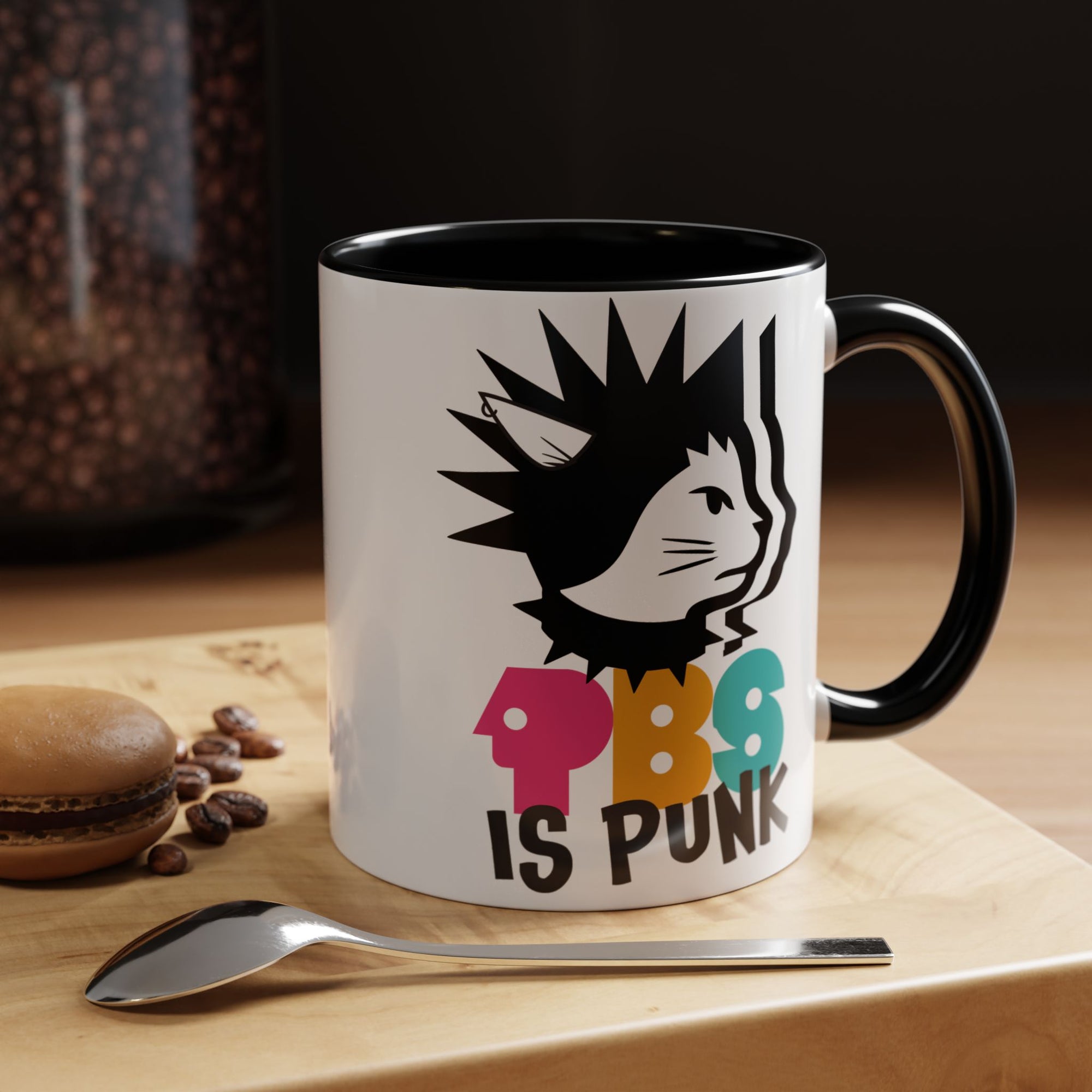 Mug with a colorful design and text on a wooden surface with coffee beans and a spoon.