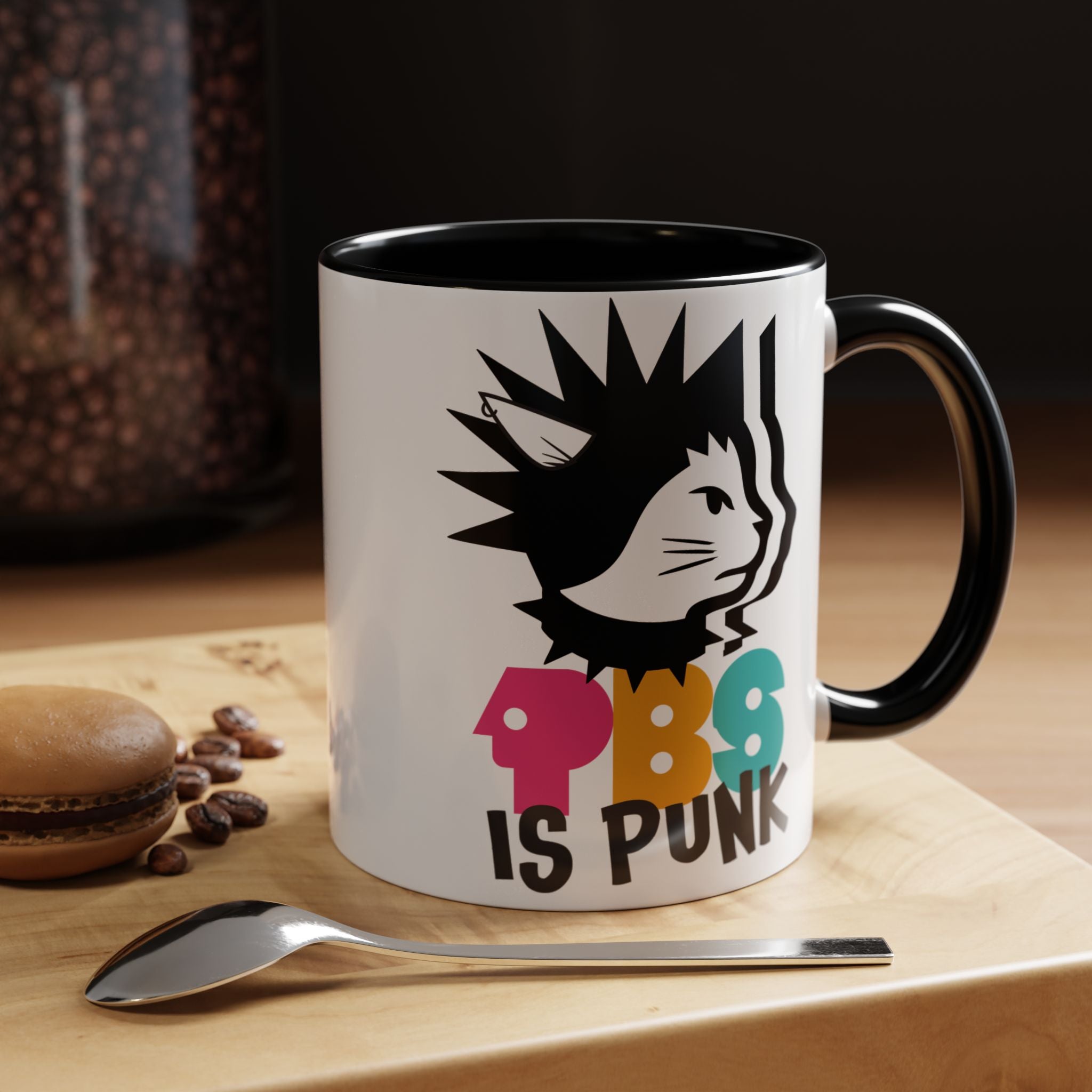Mug with a colorful design and text on a wooden surface with coffee beans and a spoon.
