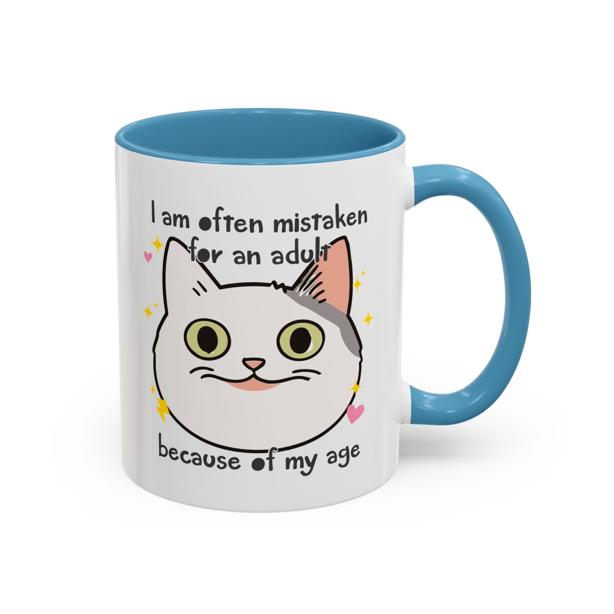 White ceramic mug with blue handle and interior featuring a cute wide-eyed cat face, hearts, sparkles, and the phrase “I am often mistaken for an adult because of my age.”
