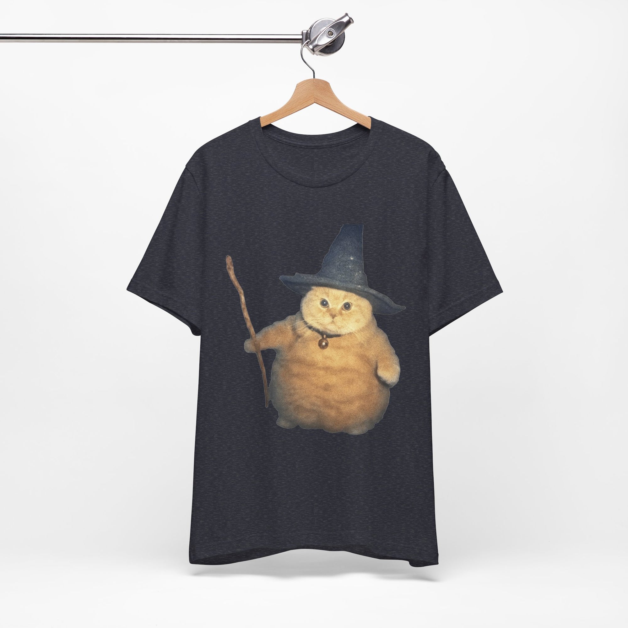 Black t-shirt with a cat wearing a witch hat and broomstick on a hanger against a white background
