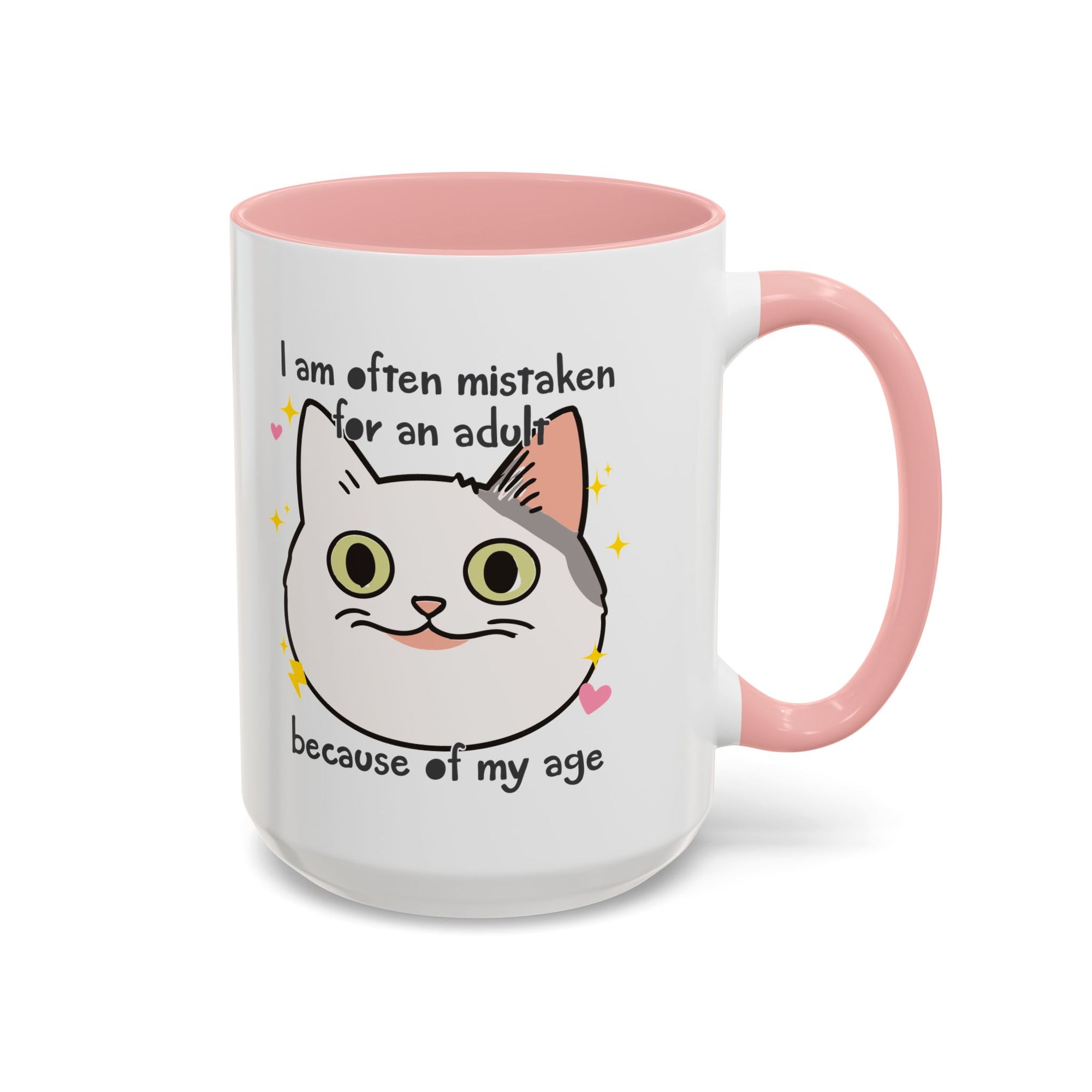 White ceramic mug with peach handle and interior featuring a cute wide-eyed cat face, hearts, sparkles, and the phrase “I am often mistaken for an adult because of my age.”
