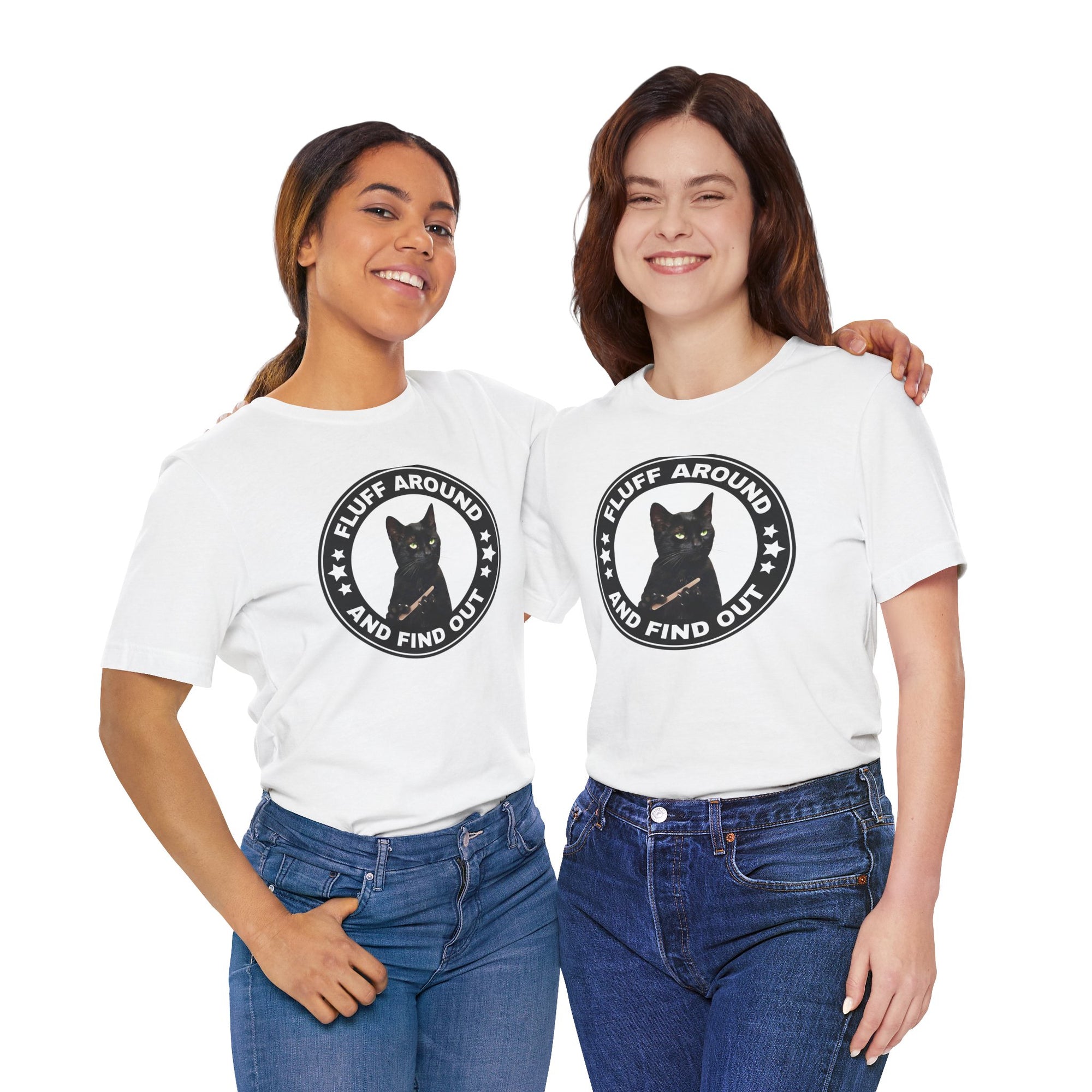 Two women wearing white t-shirt featuring a circular badge design with a black cat and the phrase “Fluff Around and Find Out.”