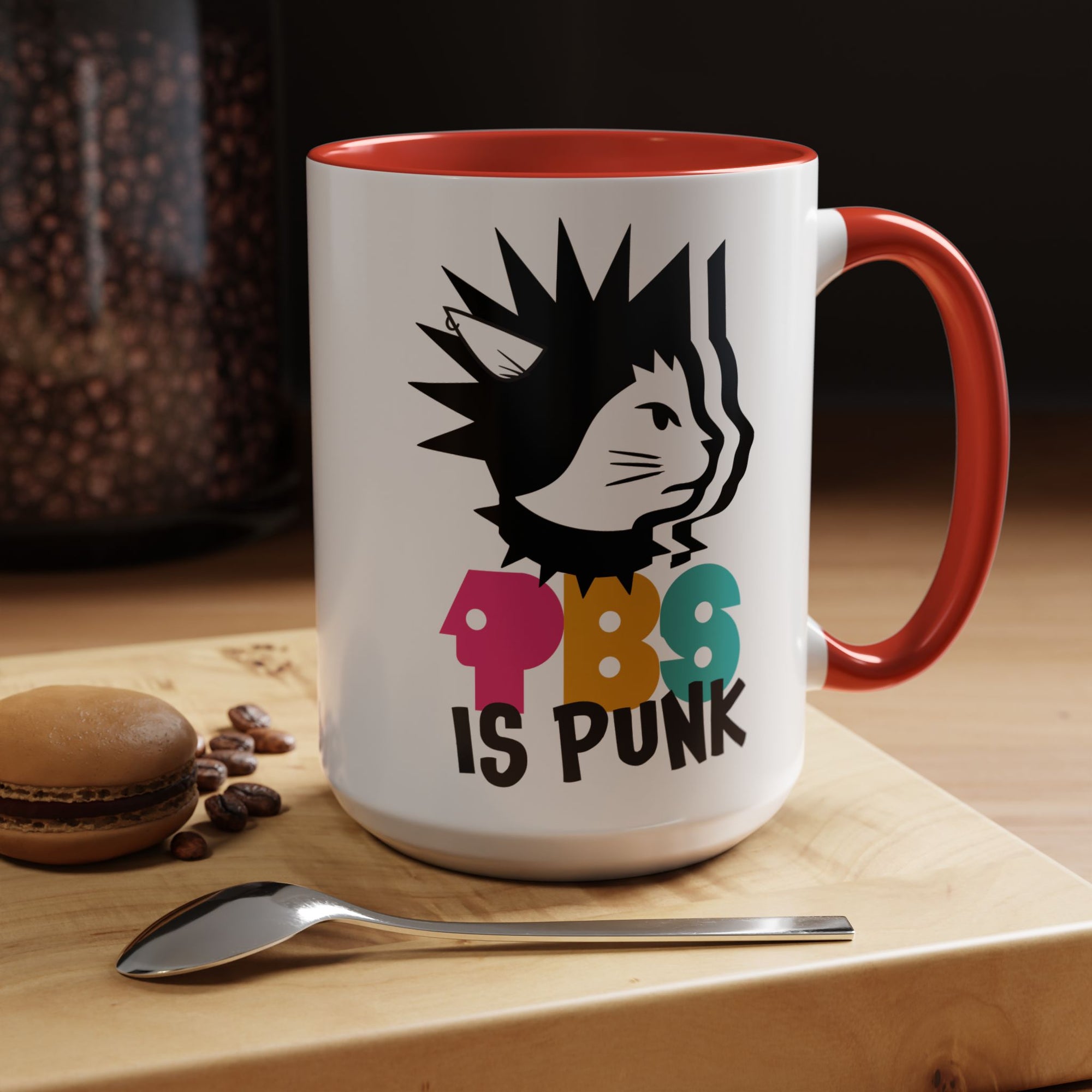 Mug with a cat graphic and 'PBC is Punk' text on a wooden surface with coffee beans and a spoon.