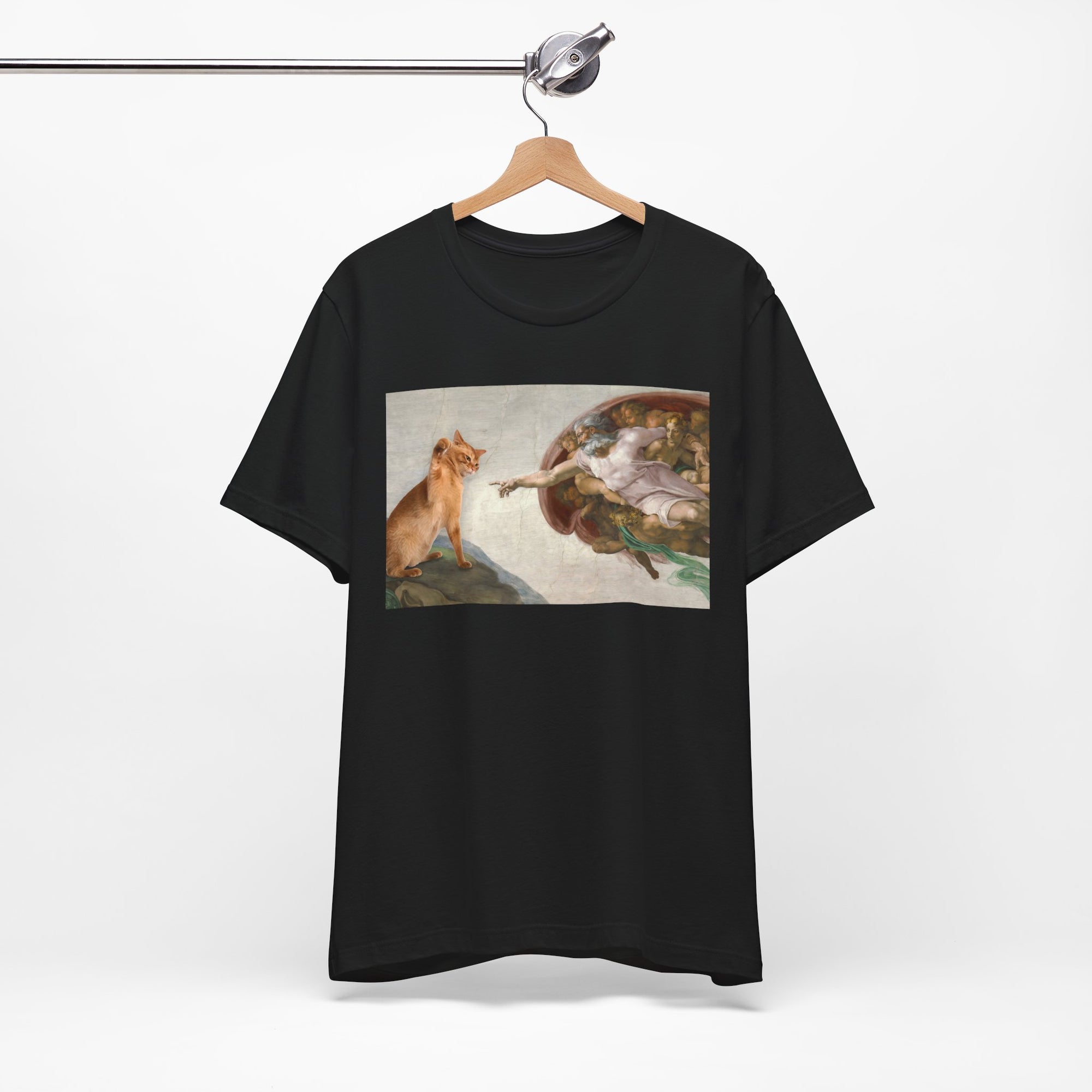 Black t-shirt with a graphic design of a cat and god on a hanger against a white background