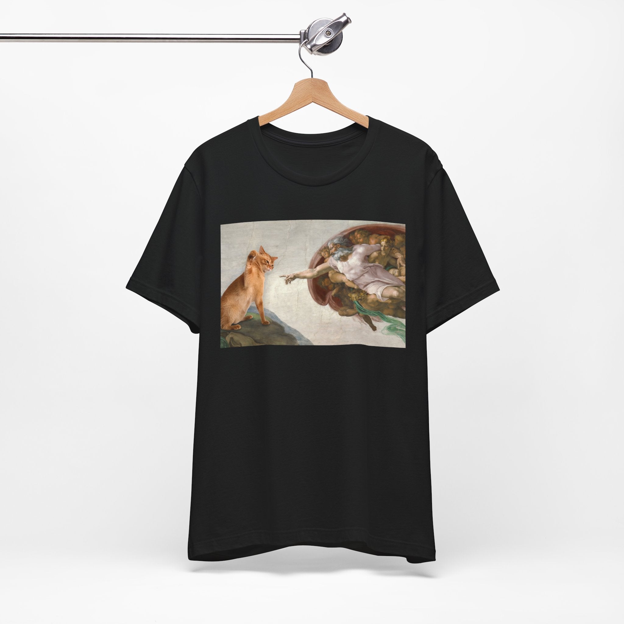 Black t-shirt with a graphic design of a cat and god on a hanger against a white background