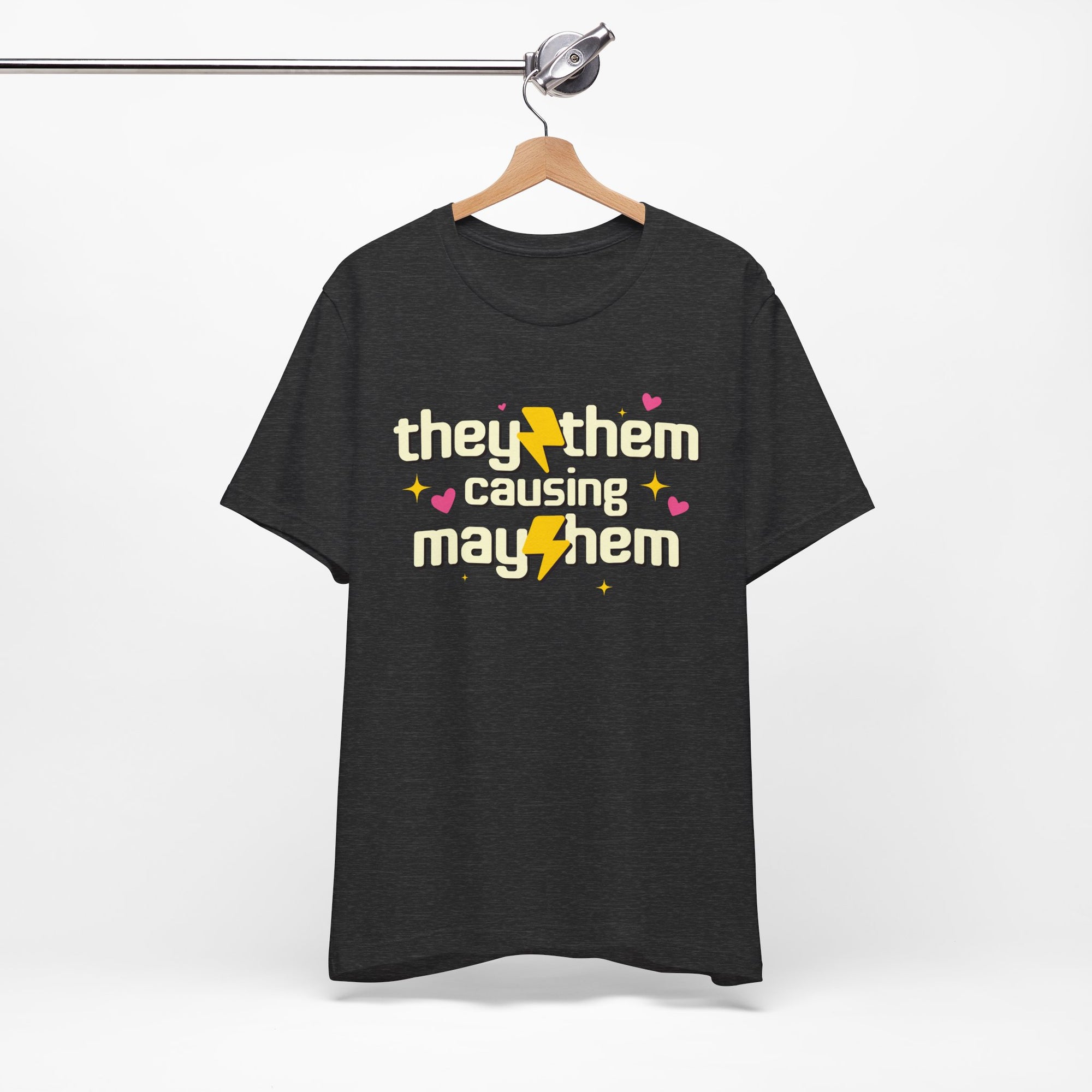 Black t-shirt with 'they/them causing mayhem' text on a hanger against a white background