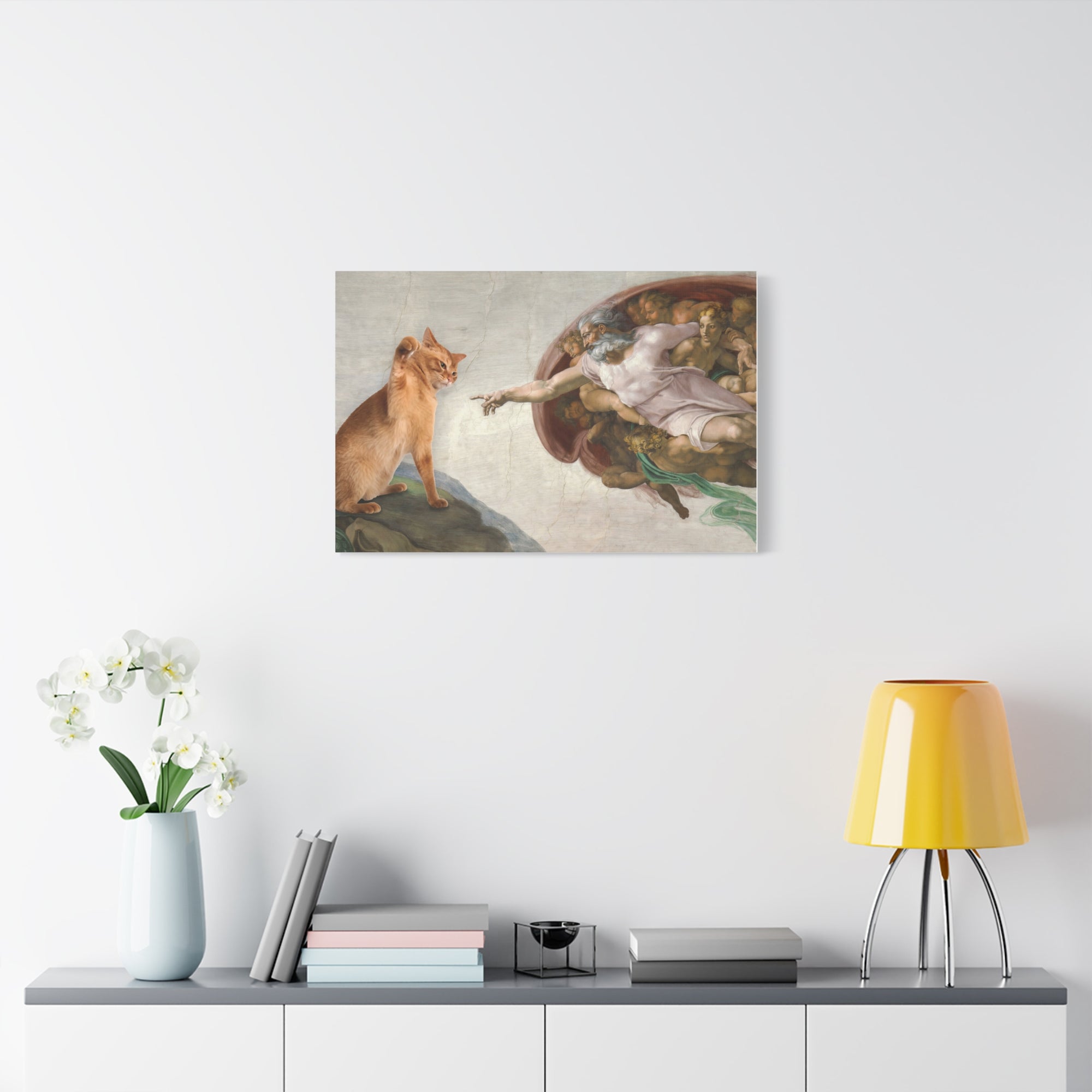 Framed artwork of a cat and a woman reaching out, above a shelf with decor items.