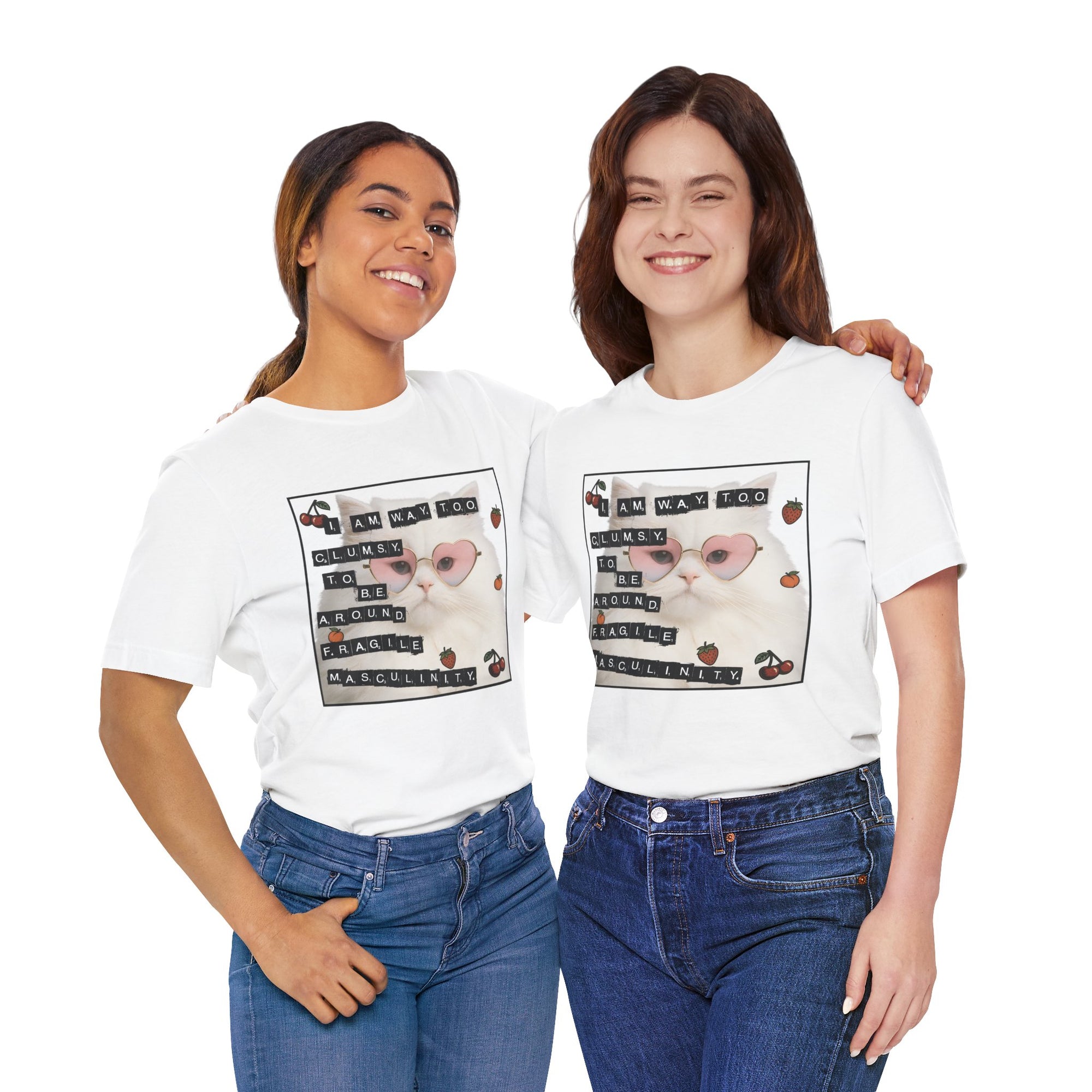 Two women wearing white t-shirt featuring a fluffy white cat in pink heart-shaped sunglasses with ransom-note style text that says “I am way too clumsy to be around fragile masculinity.”
