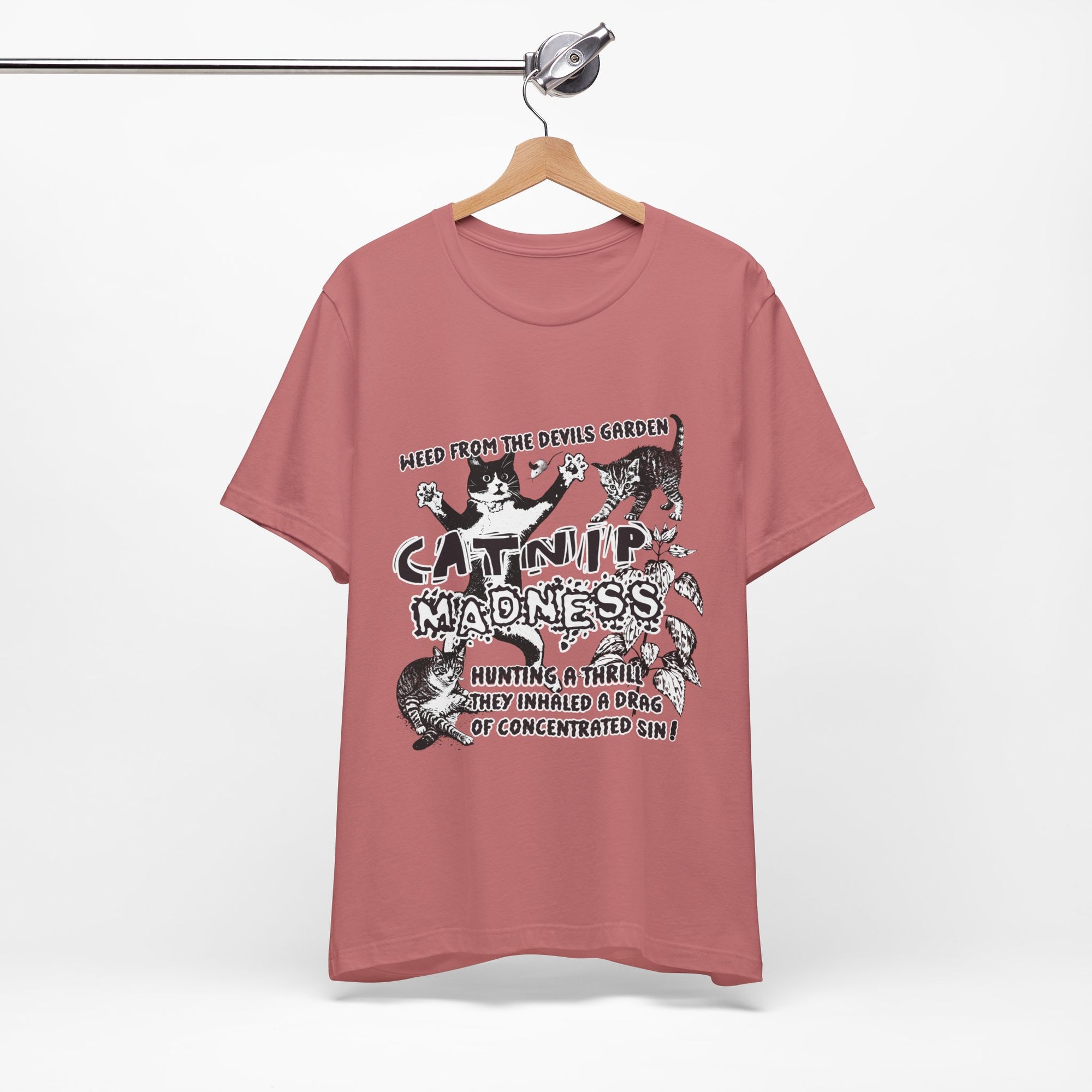 Pink t-shirt with graphic design and text on a hanger against a white background