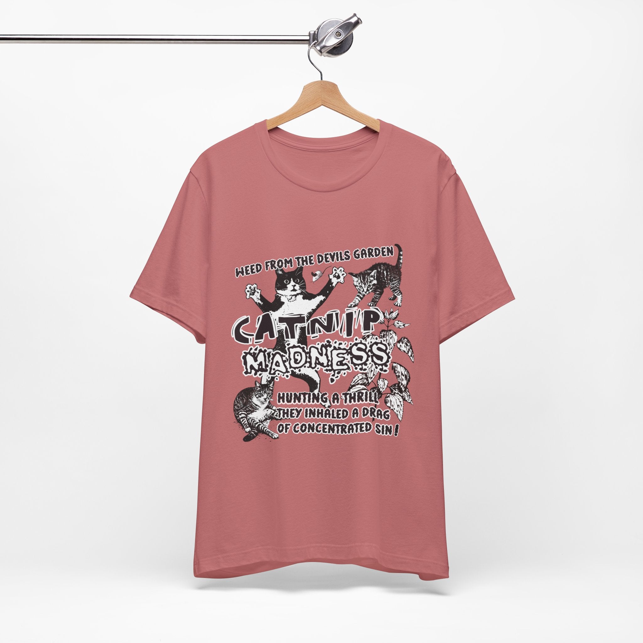 Pink t-shirt with graphic design and text on a hanger against a white background