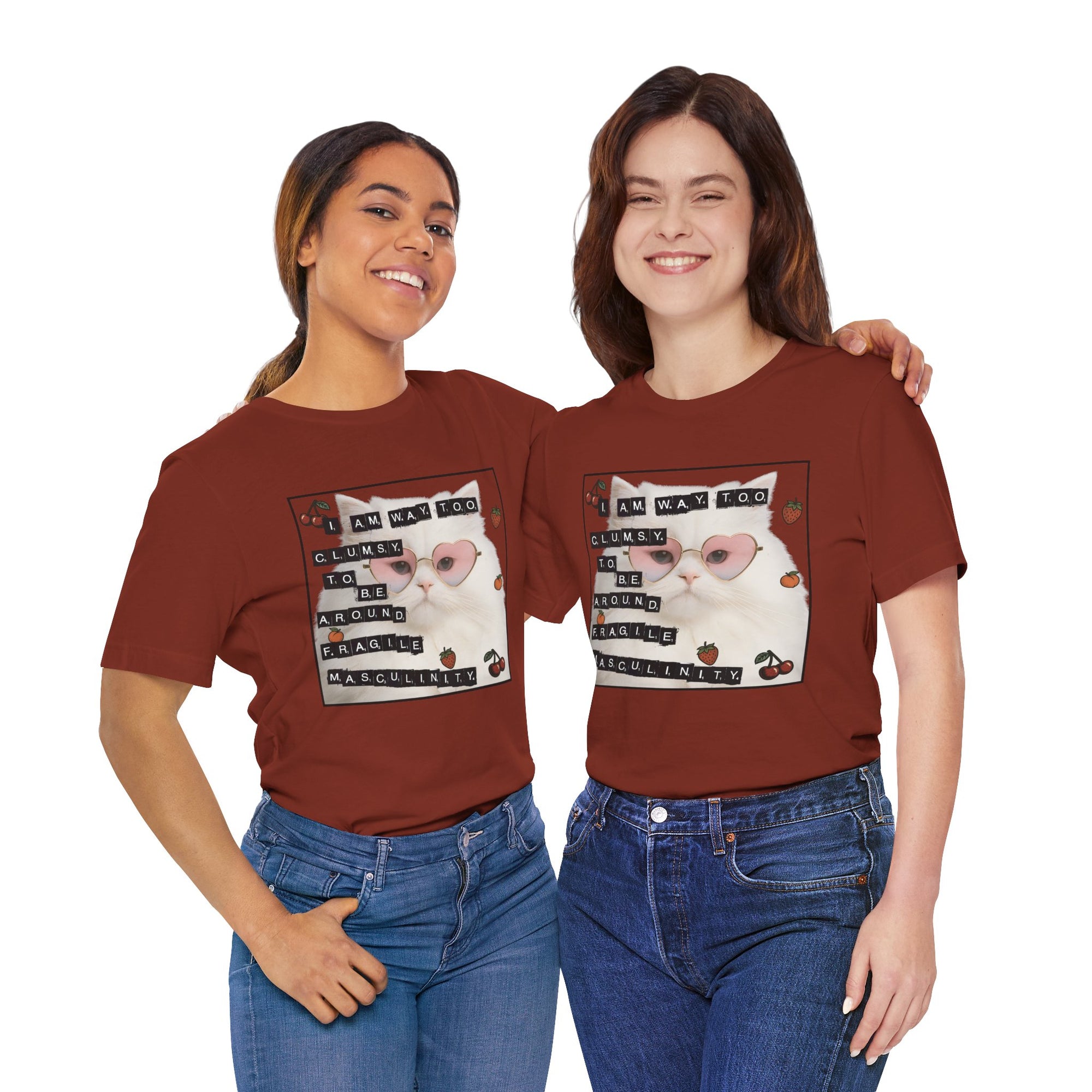 Two people wearing red t-shirt featuring a fluffy white cat in pink heart-shaped sunglasses with ransom-note style text that says “I am way too clumsy to be around fragile masculinity.”