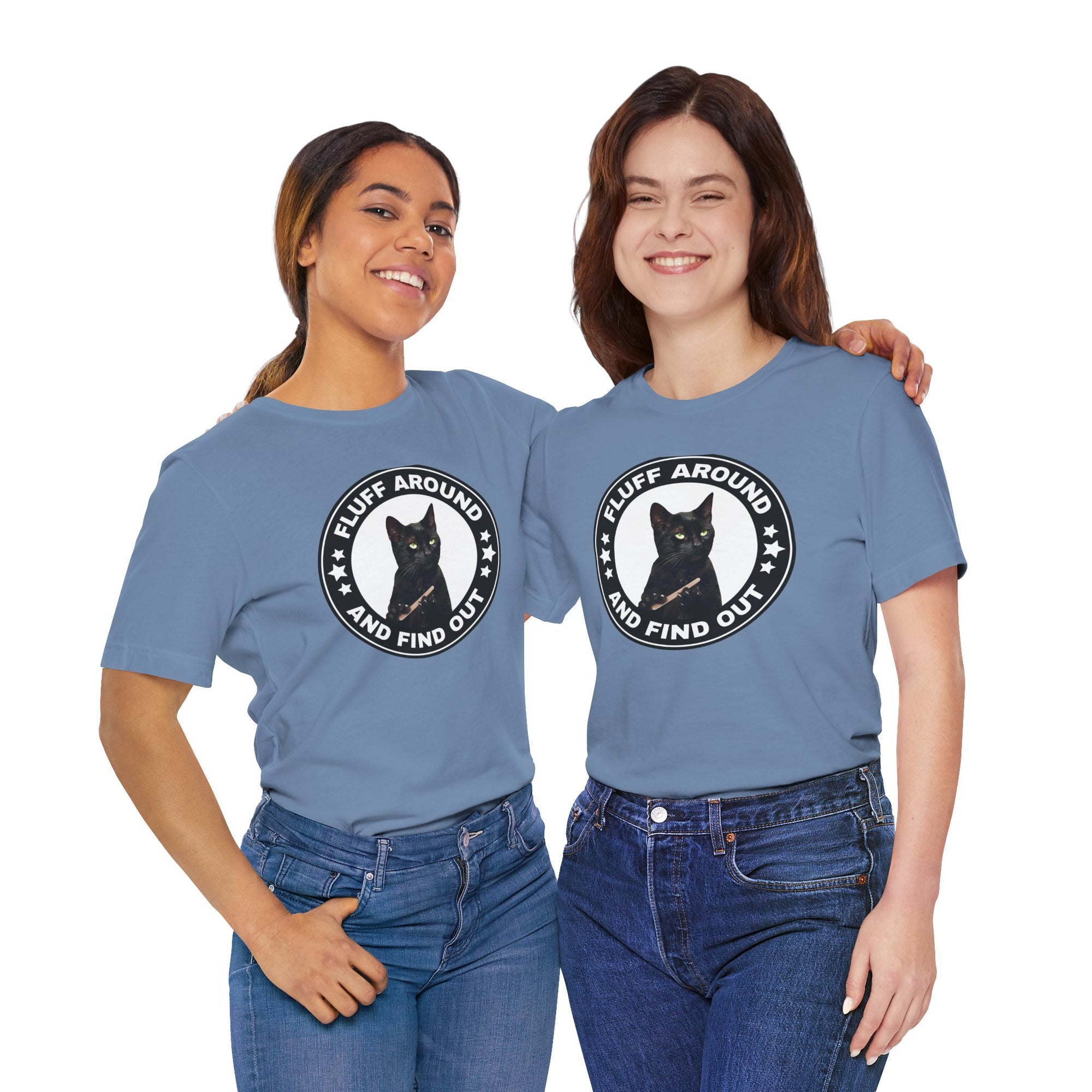 Two women wearing matching blue t-shirt featuring a circular badge design with a black cat and the phrase “Fluff Around and Find Out.”