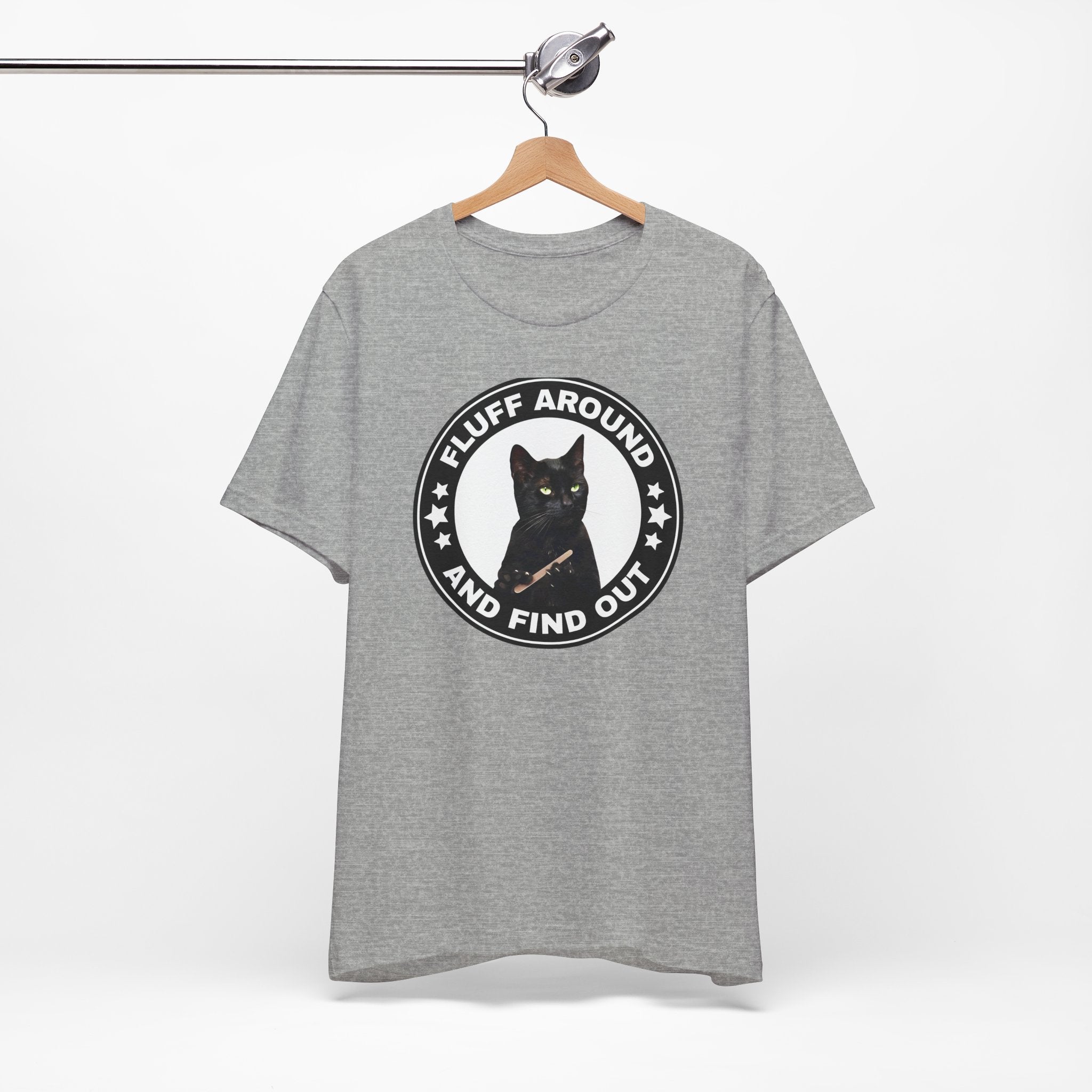 Gray t-shirt featuring a circular badge design with a black cat and the phrase “Fluff Around and Find Out.”
