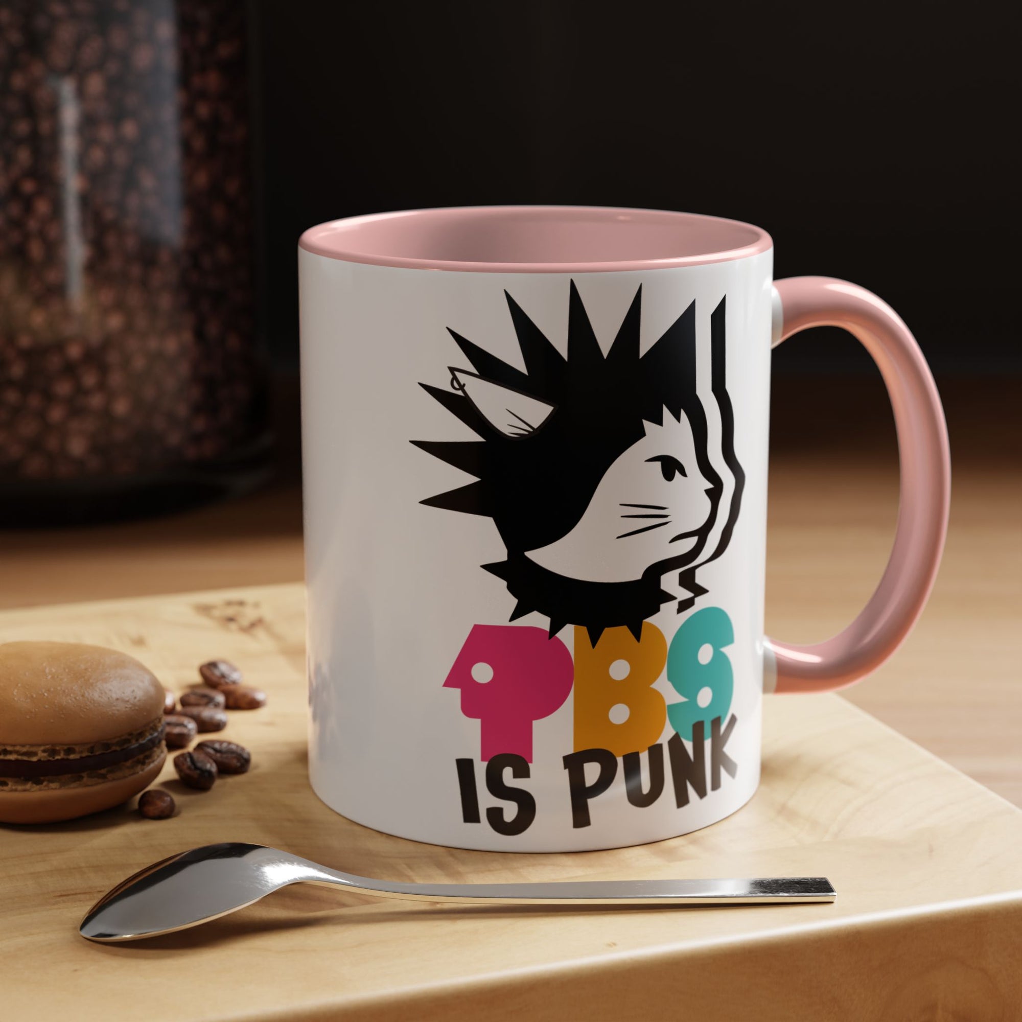 Mug with a colorful design and text on a wooden surface with coffee beans and a spoon.