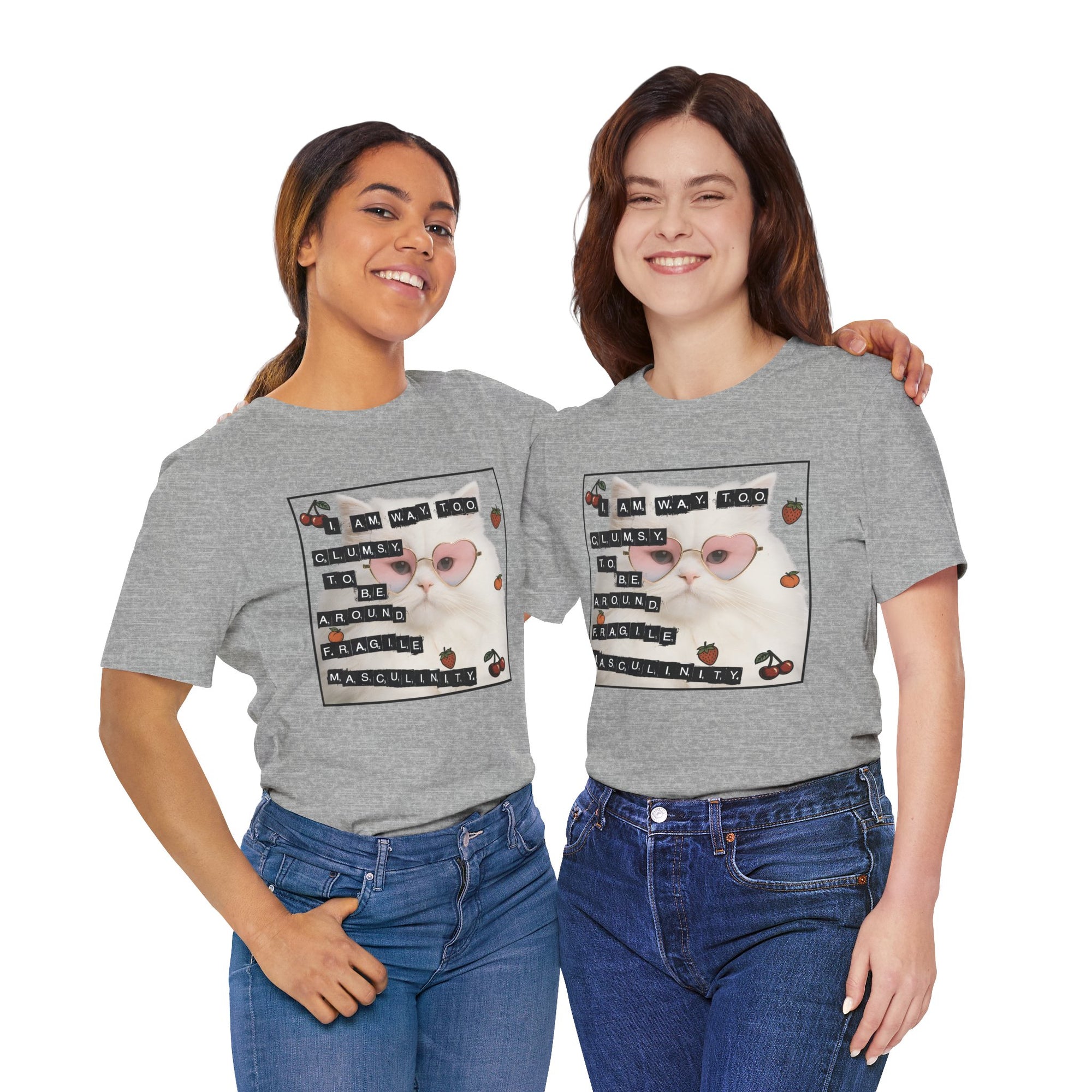 Two women wearing gray t-shirt featuring a fluffy white cat in pink heart-shaped sunglasses with ransom-note style text that says “I am way too clumsy to be around fragile masculinity.”