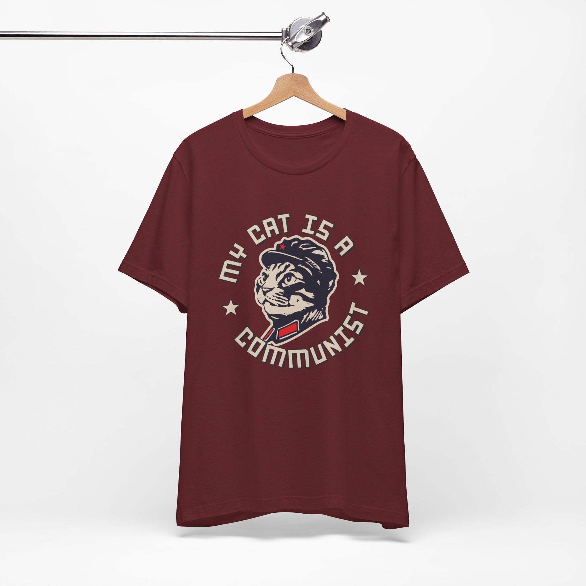 Maroon t-shirt with a graphic design of a cat and text on a hanger against a white background