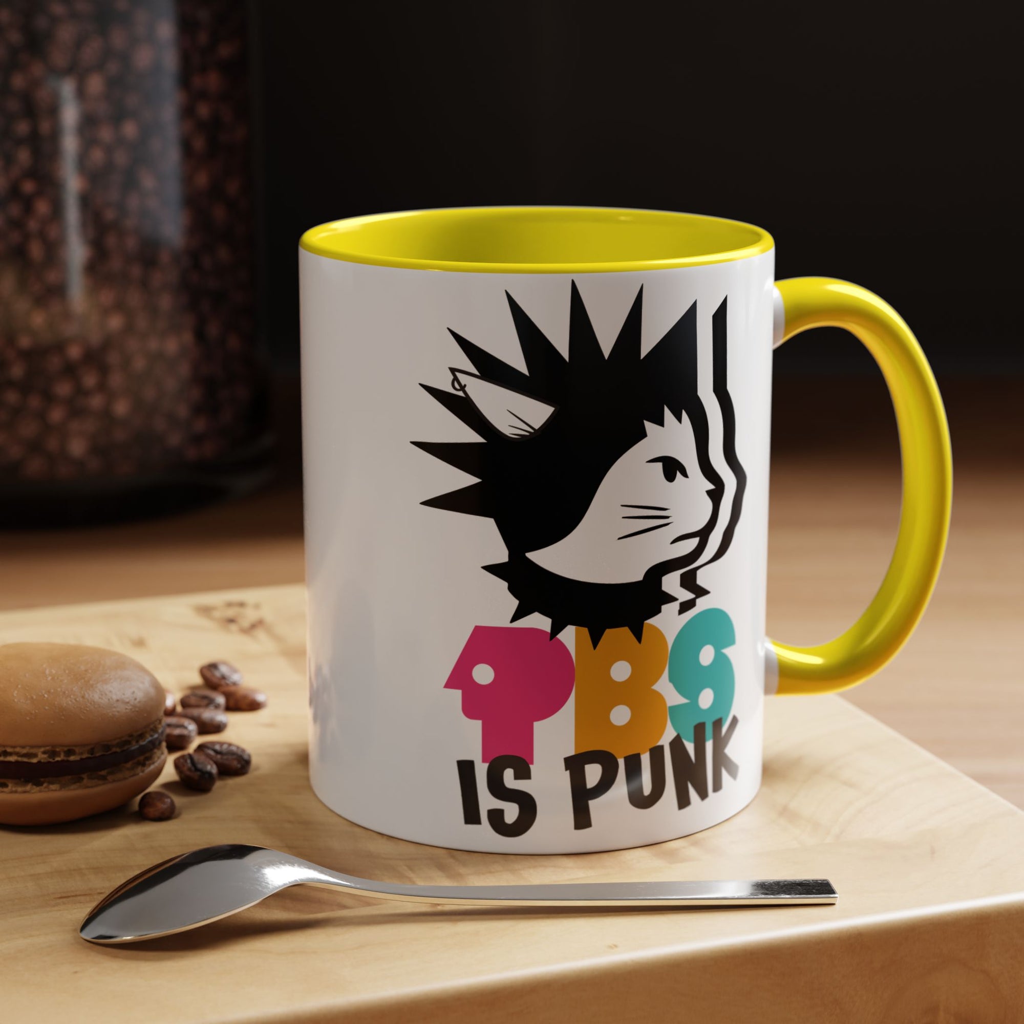 Mug with colorful design and text on a wooden surface with coffee beans and a spoon.