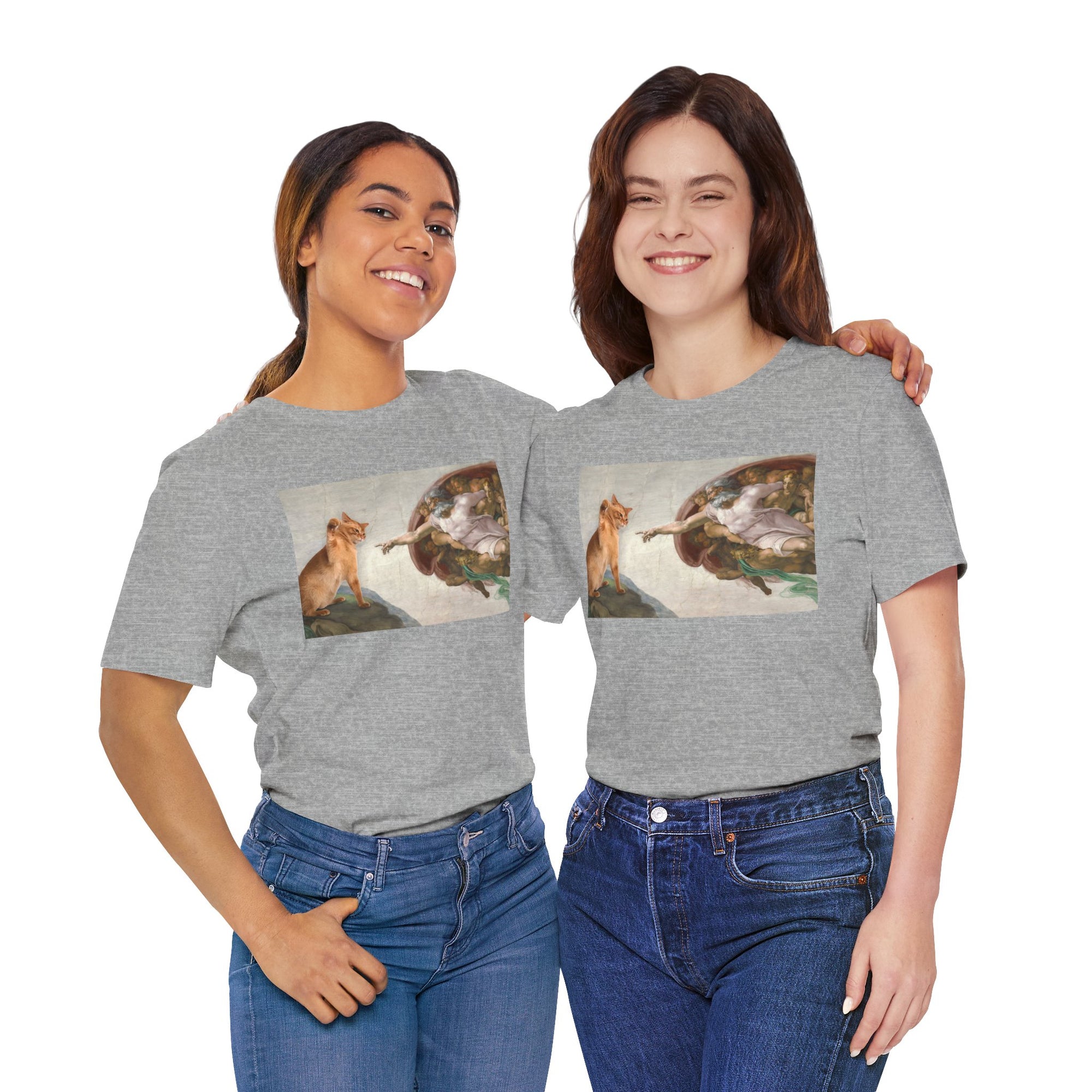 Two women wearing gray t-shirts with a graphic design of a cat and god on a white background.