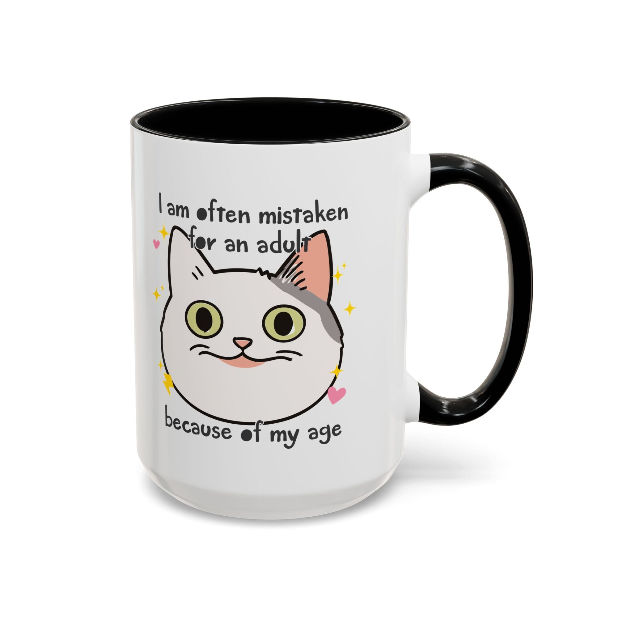 White ceramic mug with black handle and interior featuring a cute wide-eyed cat face, hearts, sparkles, and the phrase “I am often mistaken for an adult because of my age.”
