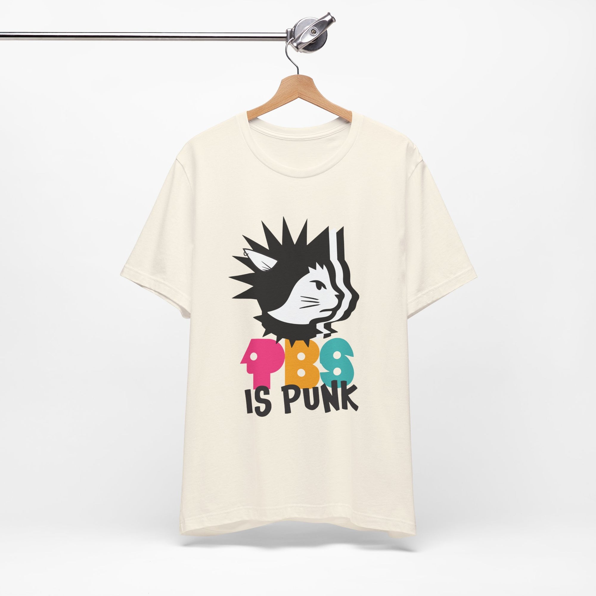 Beige t-shirt featuring a punk-style black cat graphic with colorful letters spelling “PBG” and black text that says “Is Punk.”
