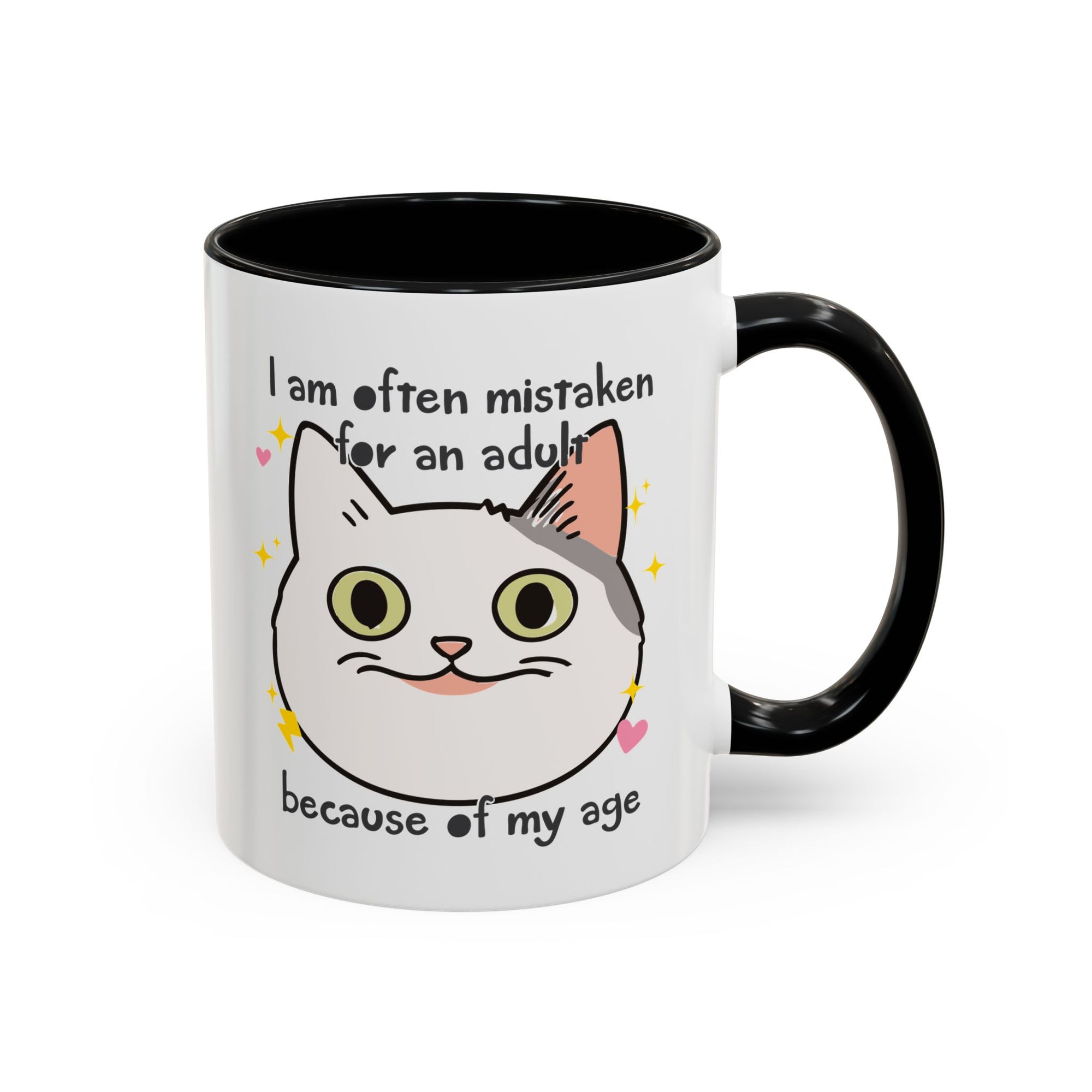 White ceramic mug with black handle and interior featuring a cute wide-eyed cat face, hearts, sparkles, and the phrase “I am often mistaken for an adult because of my age.”
