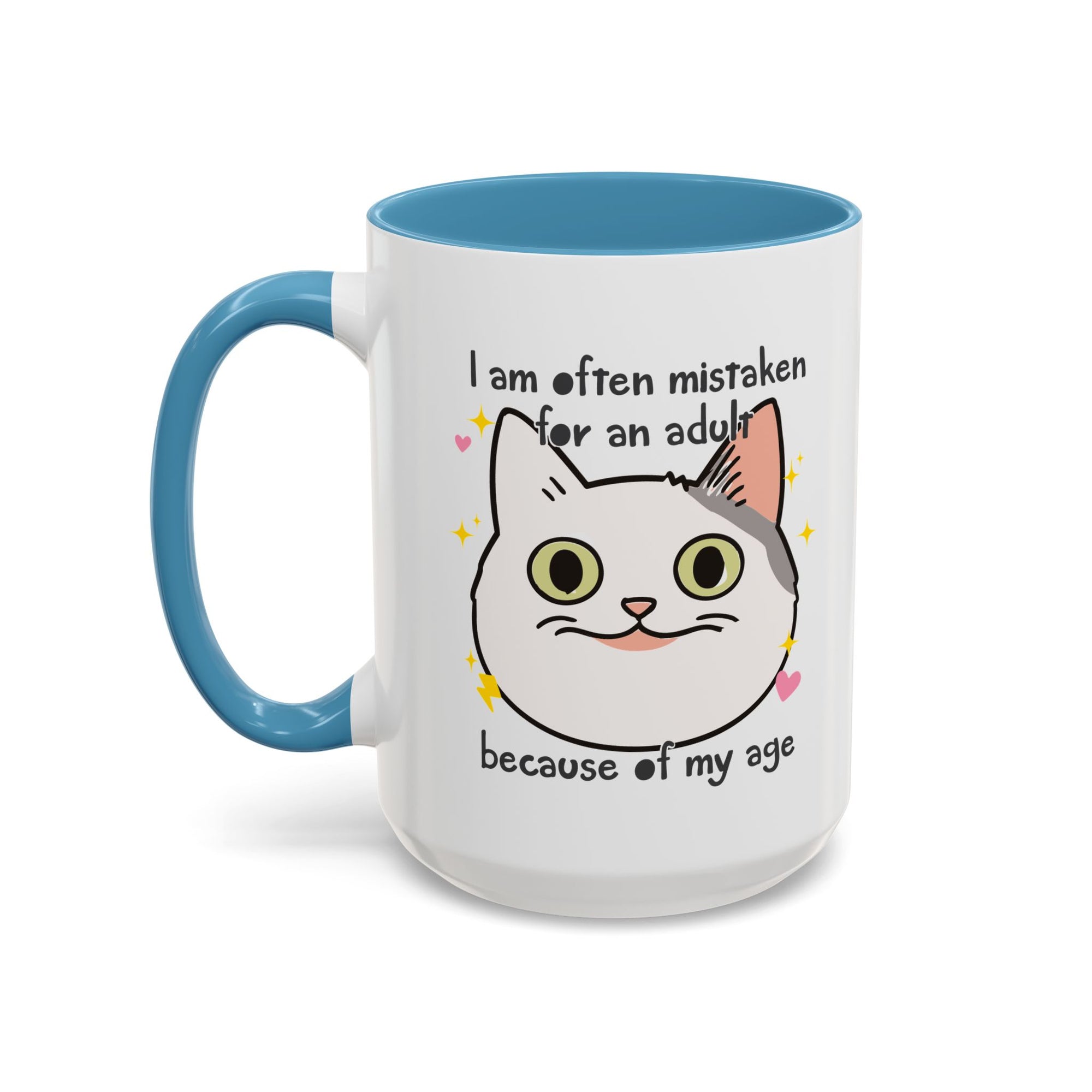 White ceramic mug with blue handle and interior featuring a cute wide-eyed cat face, hearts, sparkles, and the phrase “I am often mistaken for an adult because of my age.”
