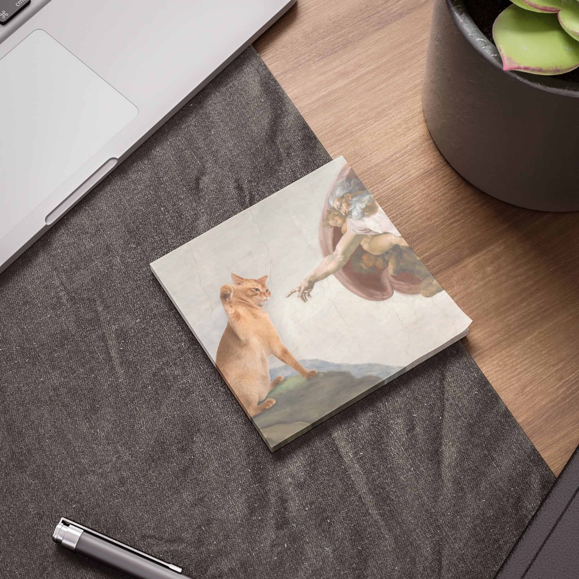 Post-it notes with a cat and angel design on a desk next to a laptop and plant