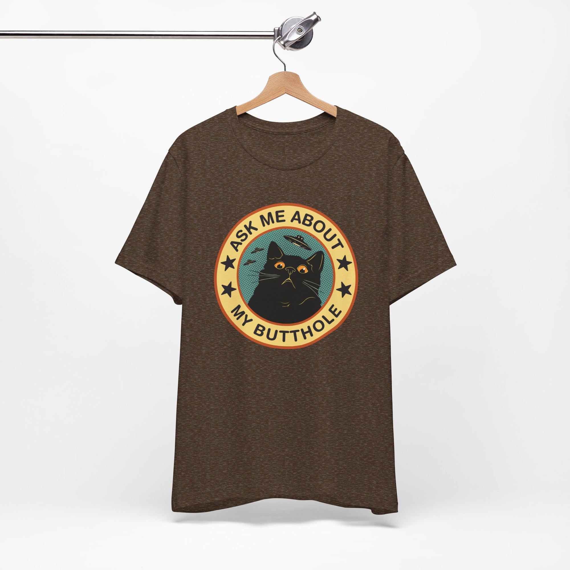 Brown t-shirt with a graphic design of a cat and text on a hanger against a white background