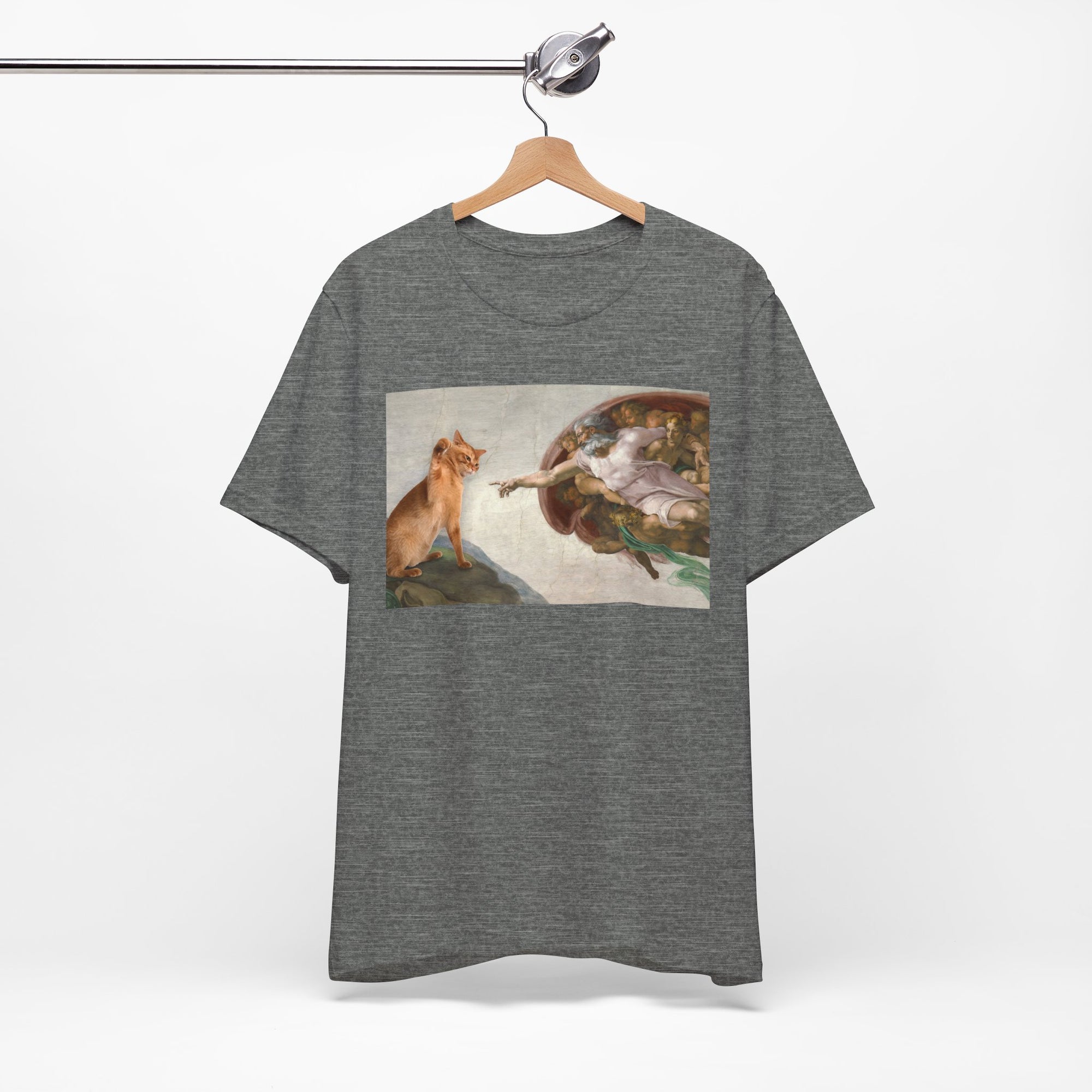 Gray t-shirt with a graphic design of a cat and god on a hanger against a white background