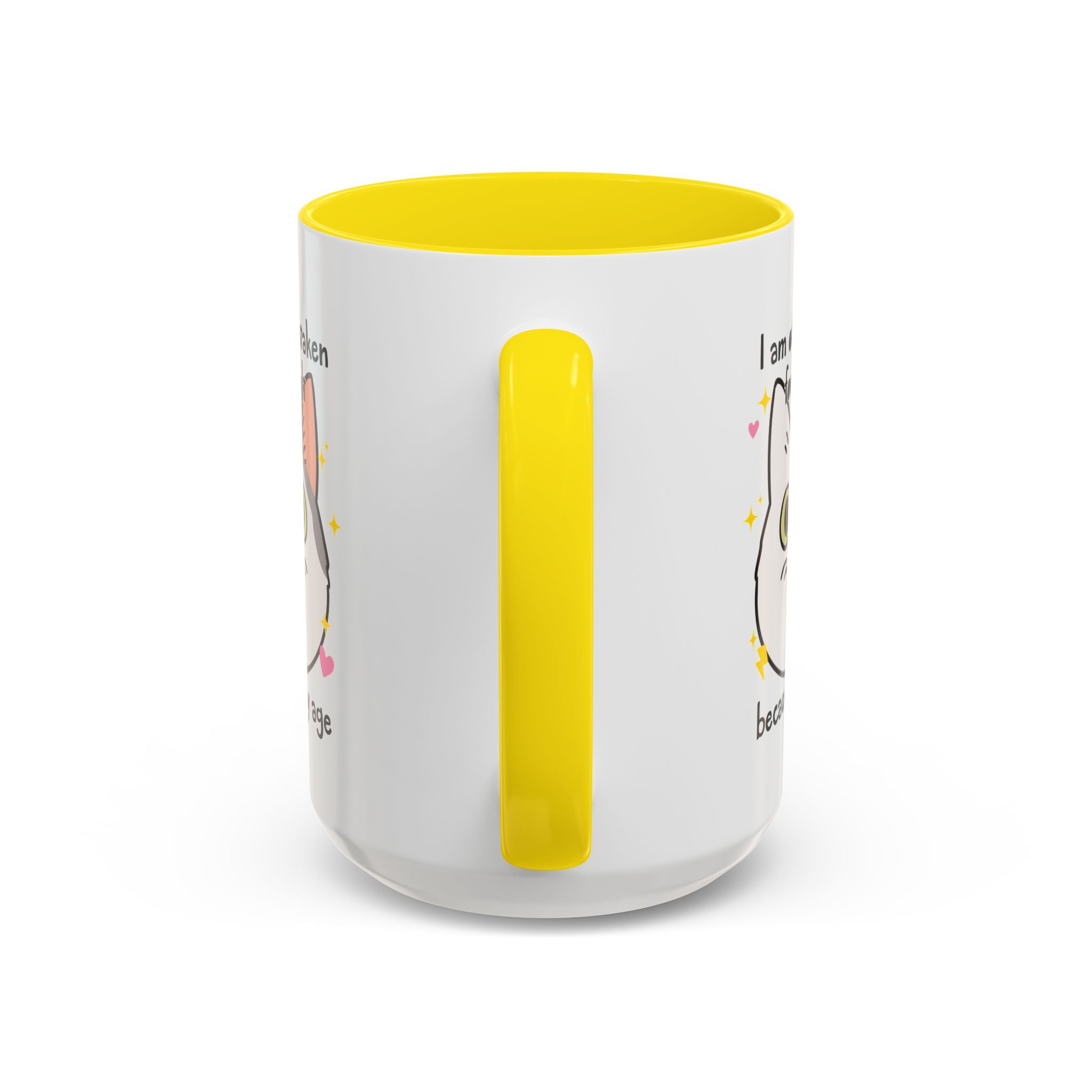 White ceramic mug with yellow handle and interior featuring a cute wide-eyed cat face, hearts, sparkles, and the phrase “I am often mistaken for an adult because of my age.”
