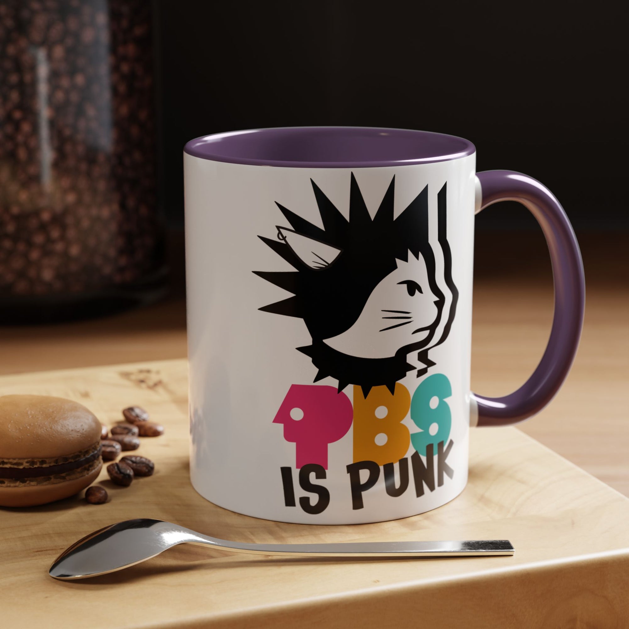 Mug with a colorful design and text on a wooden surface with coffee beans and a spoon.