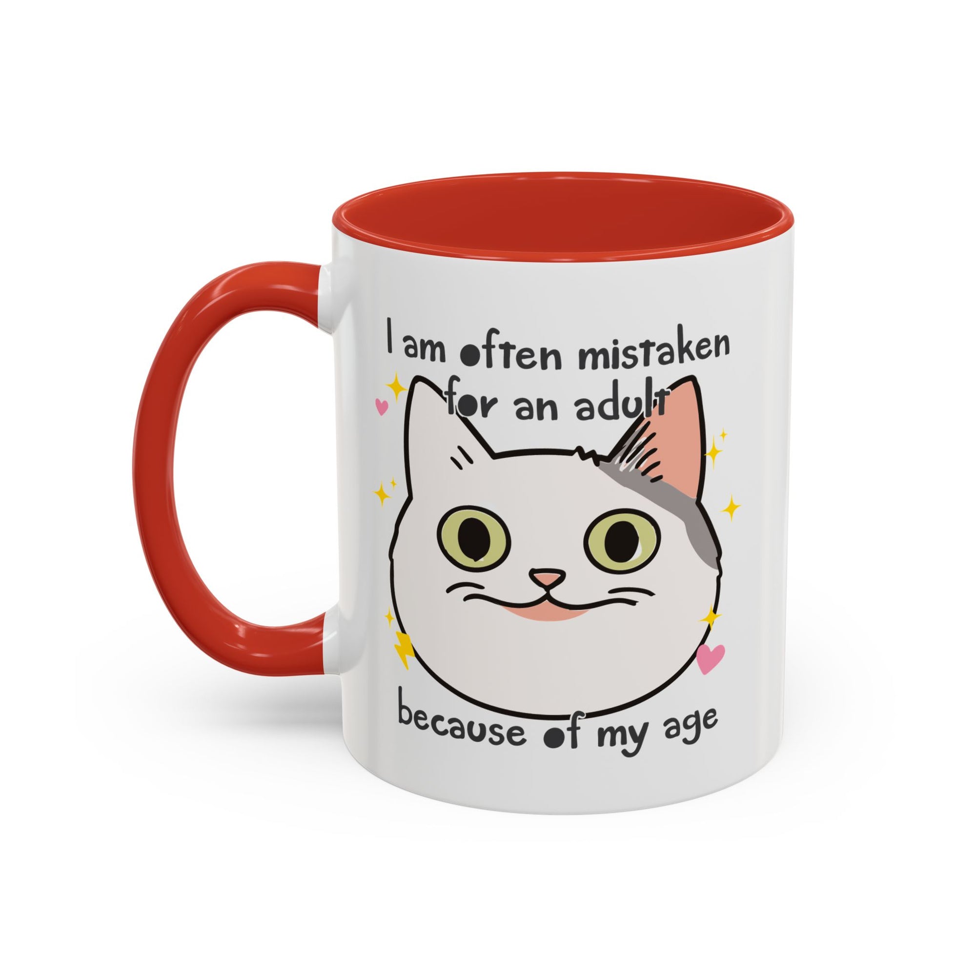 White ceramic mug with red handle and interior featuring a cute wide-eyed cat face, hearts, sparkles, and the phrase “I am often mistaken for an adult because of my age.”
