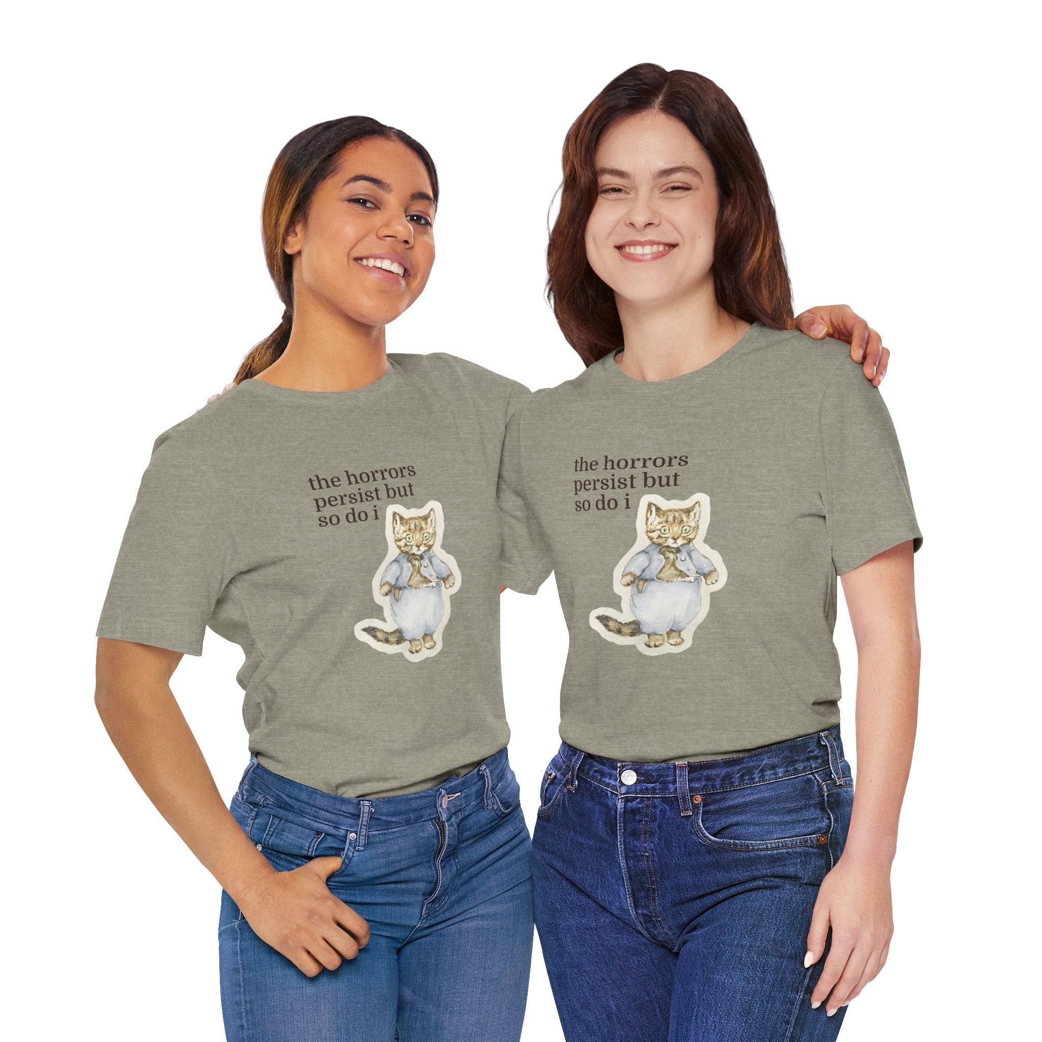 Two people wearing matching green t-shirt featuring a vintage-style illustrated cat in blue clothing with the phrase “the horrors persist but so do i.”