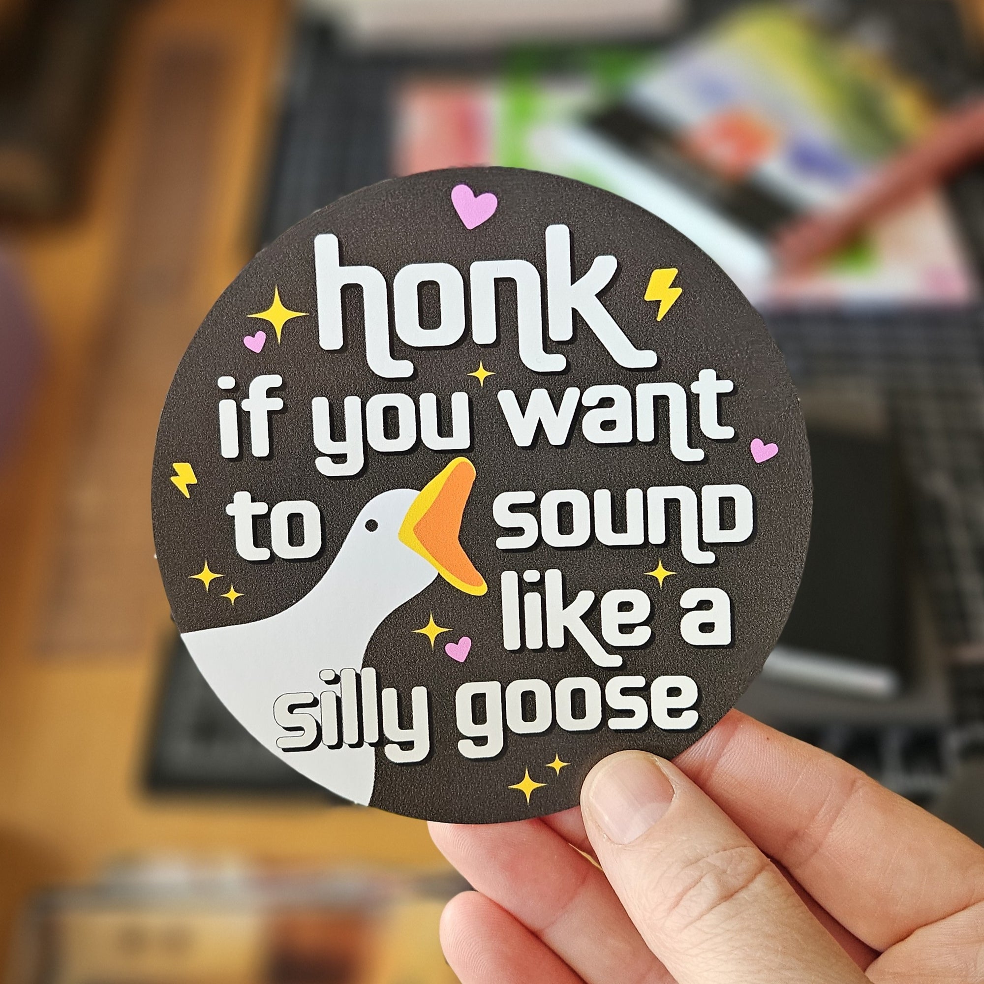 round vinyl sticker, black, with a goose face and the phrase “honk if you want to sound like a silly goose.”
