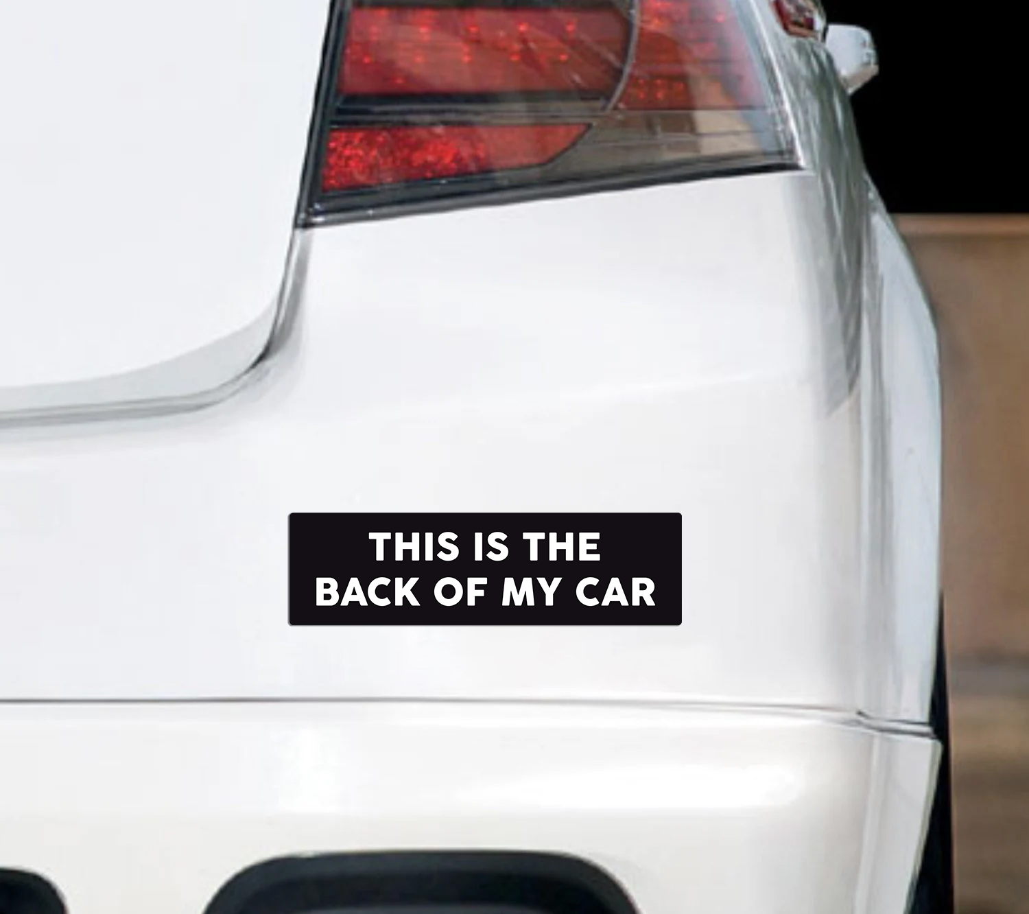 Rectangular black bumper sticker with bold white text that says “This Is the Back of My Car.”
